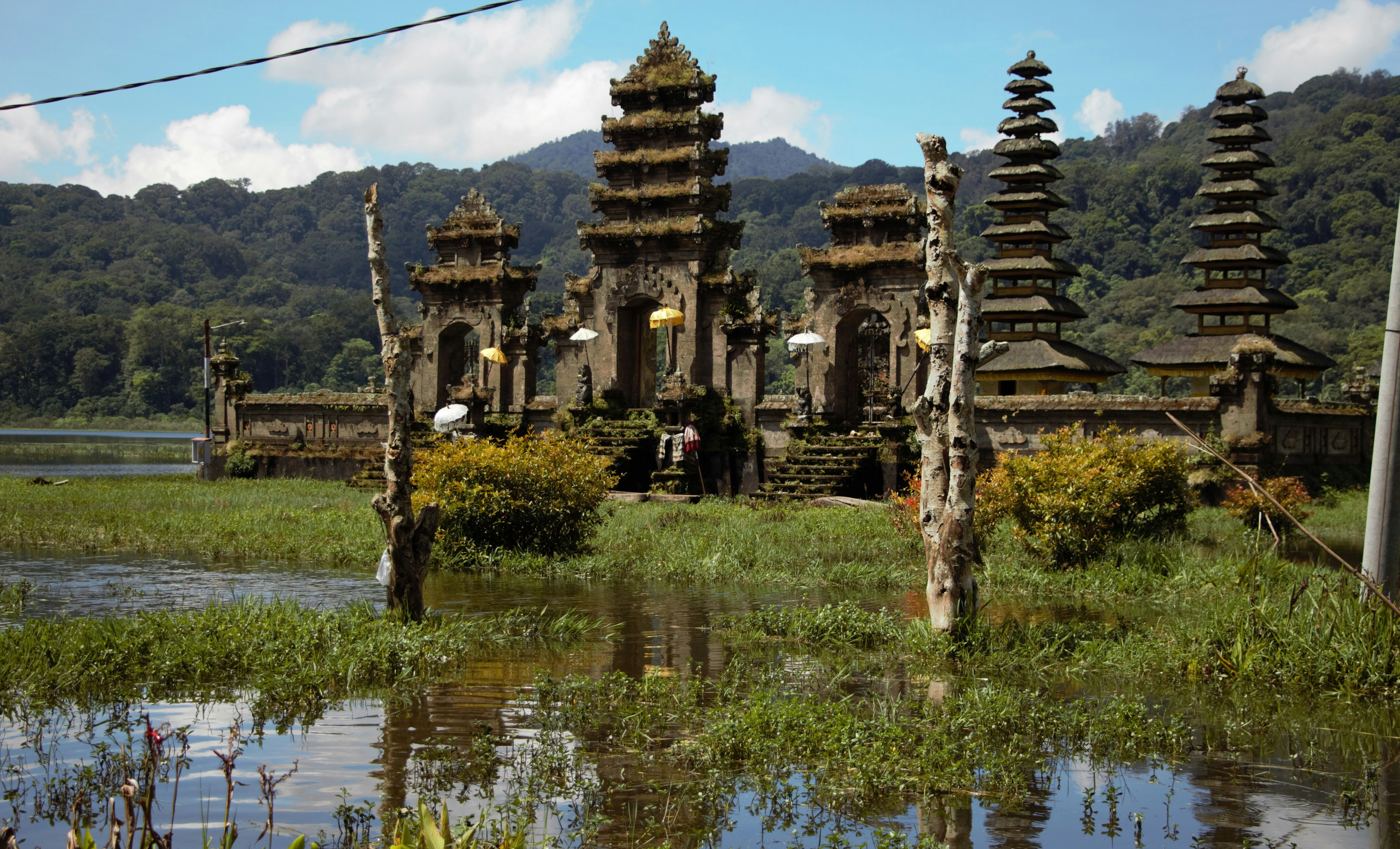 a building with towers and trees in front of a body of water