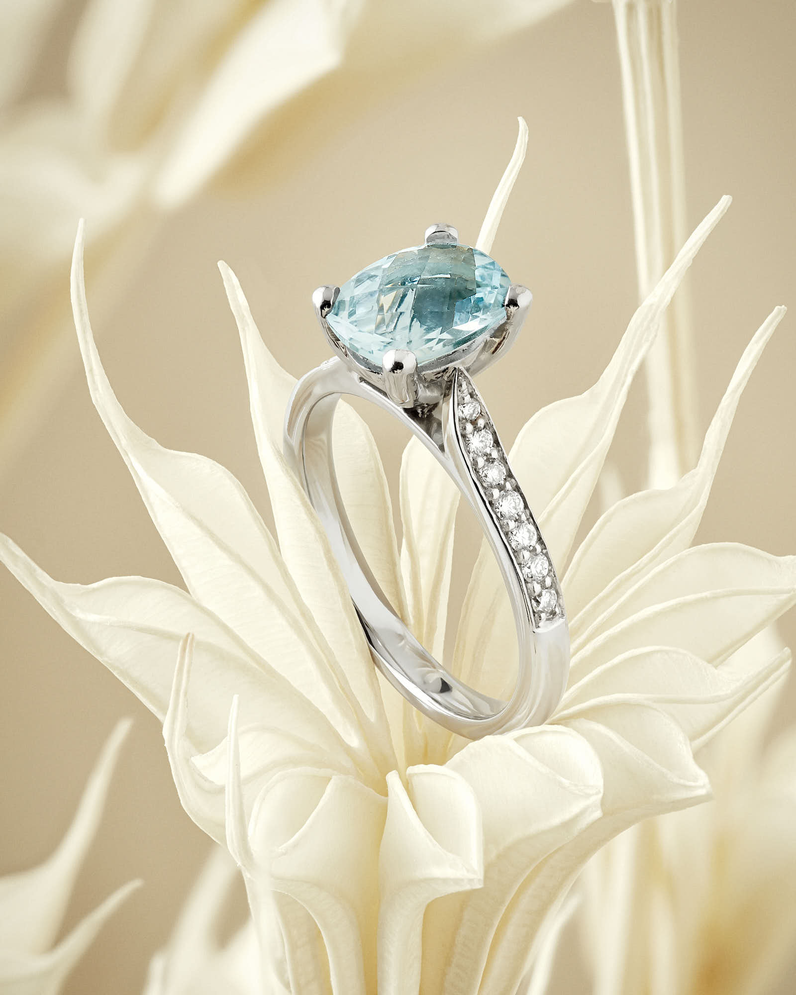 Elegant aquamarine engagement ring with diamond accents on floral background.