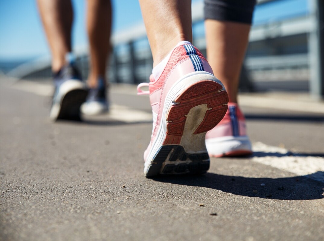 feet of a couple walking to lose weight along a promenade in the summertime
