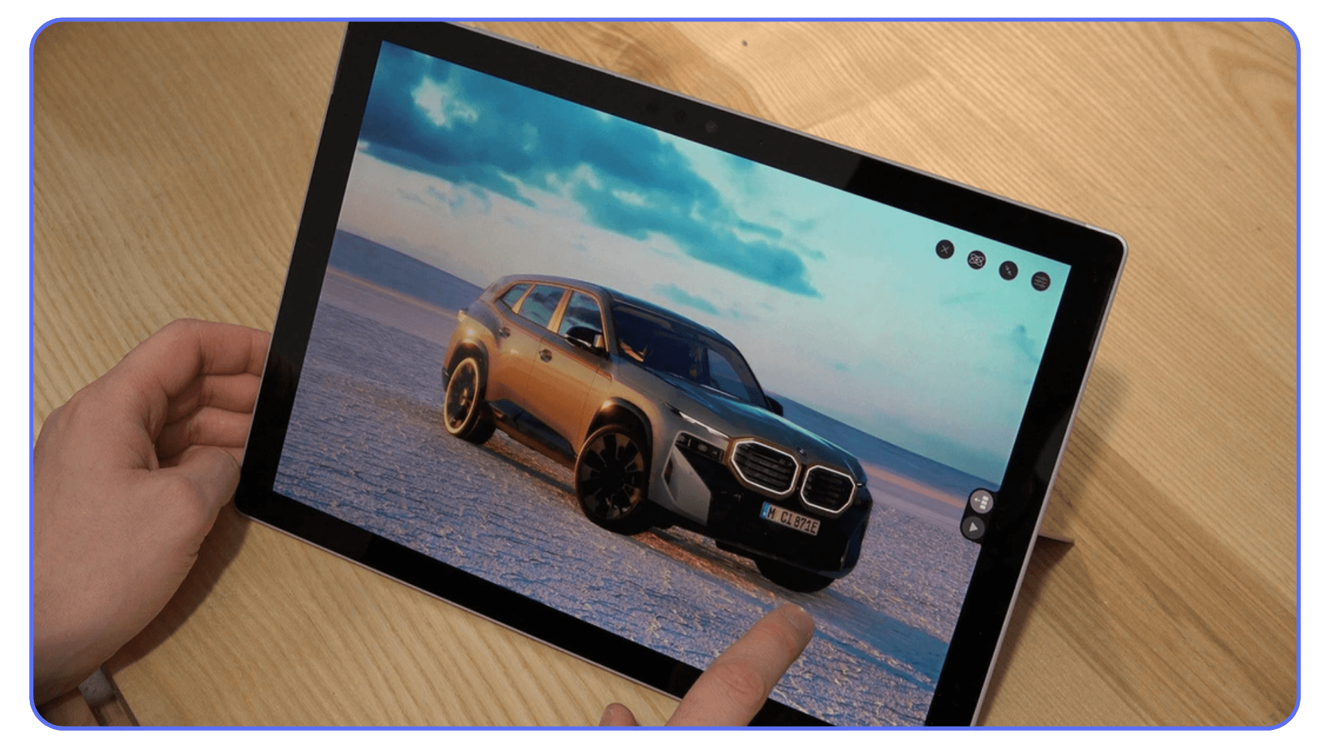 A person interacting with a tablet showing a 3D render of a BMW SUV parked on a salt flat, adjusting the view with a fingertip.