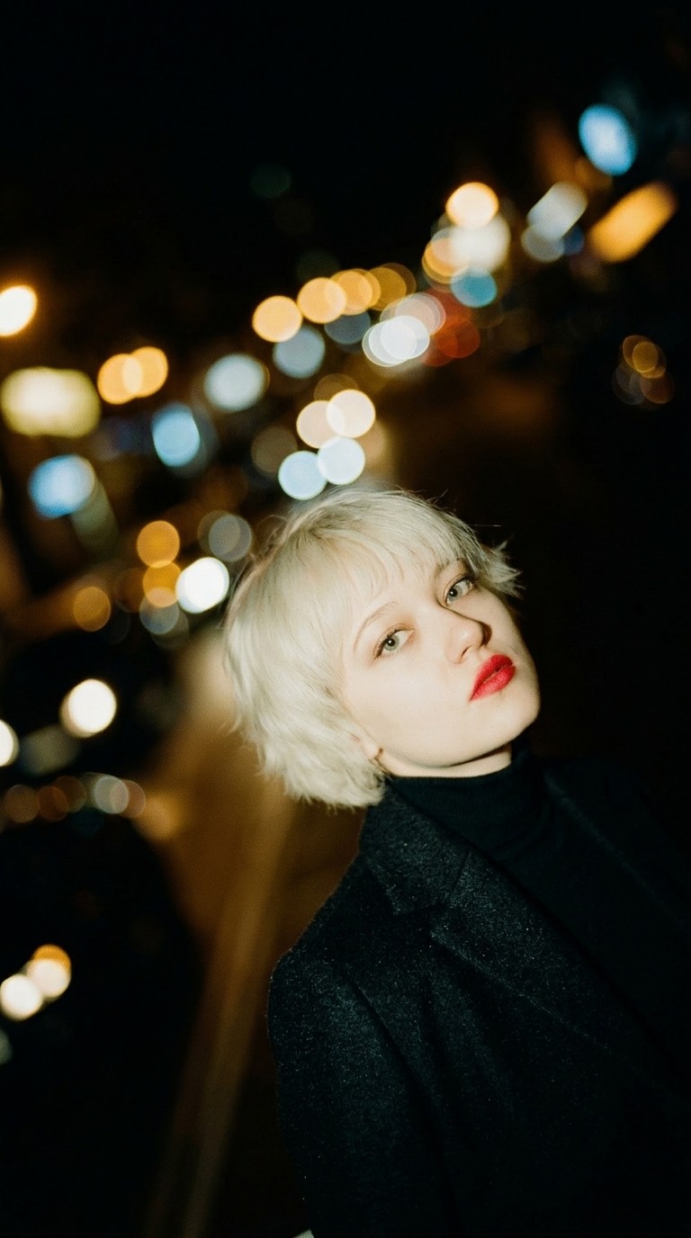 Close up of a woman with short blonde hair in a dark city setting