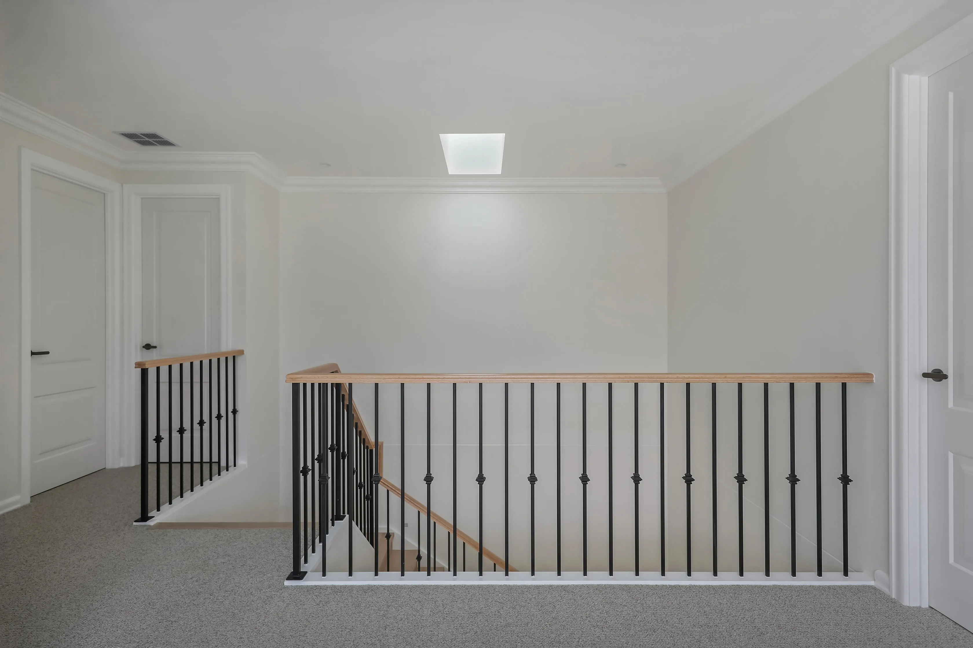 Templestowe upstairs landing with carpet, a skylight and a timber handrail with black wrought-iron balustrade