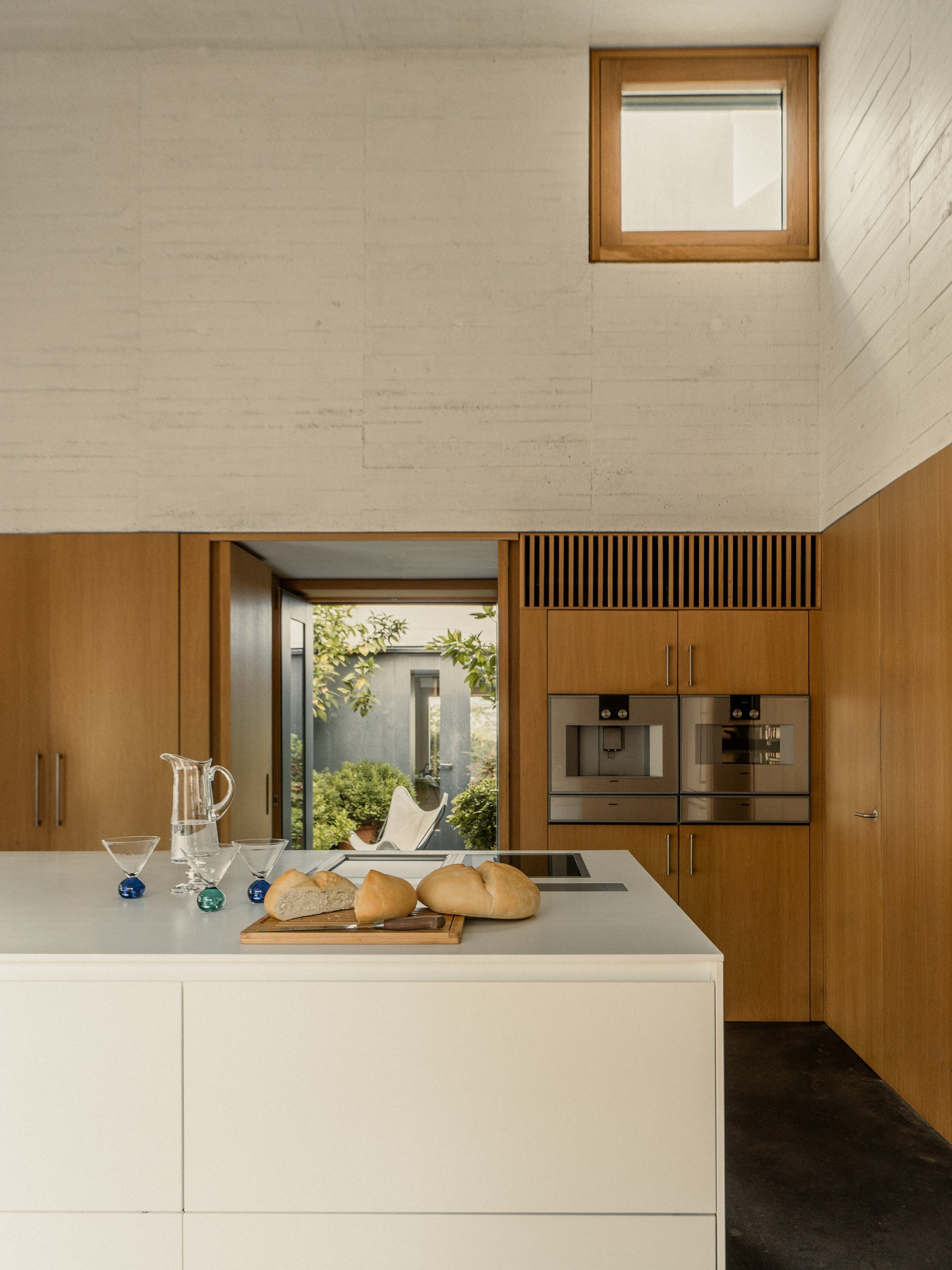 Kitchen with white island and wood-paneled walls in a house in Cáceres by Tuñón y Albornoz