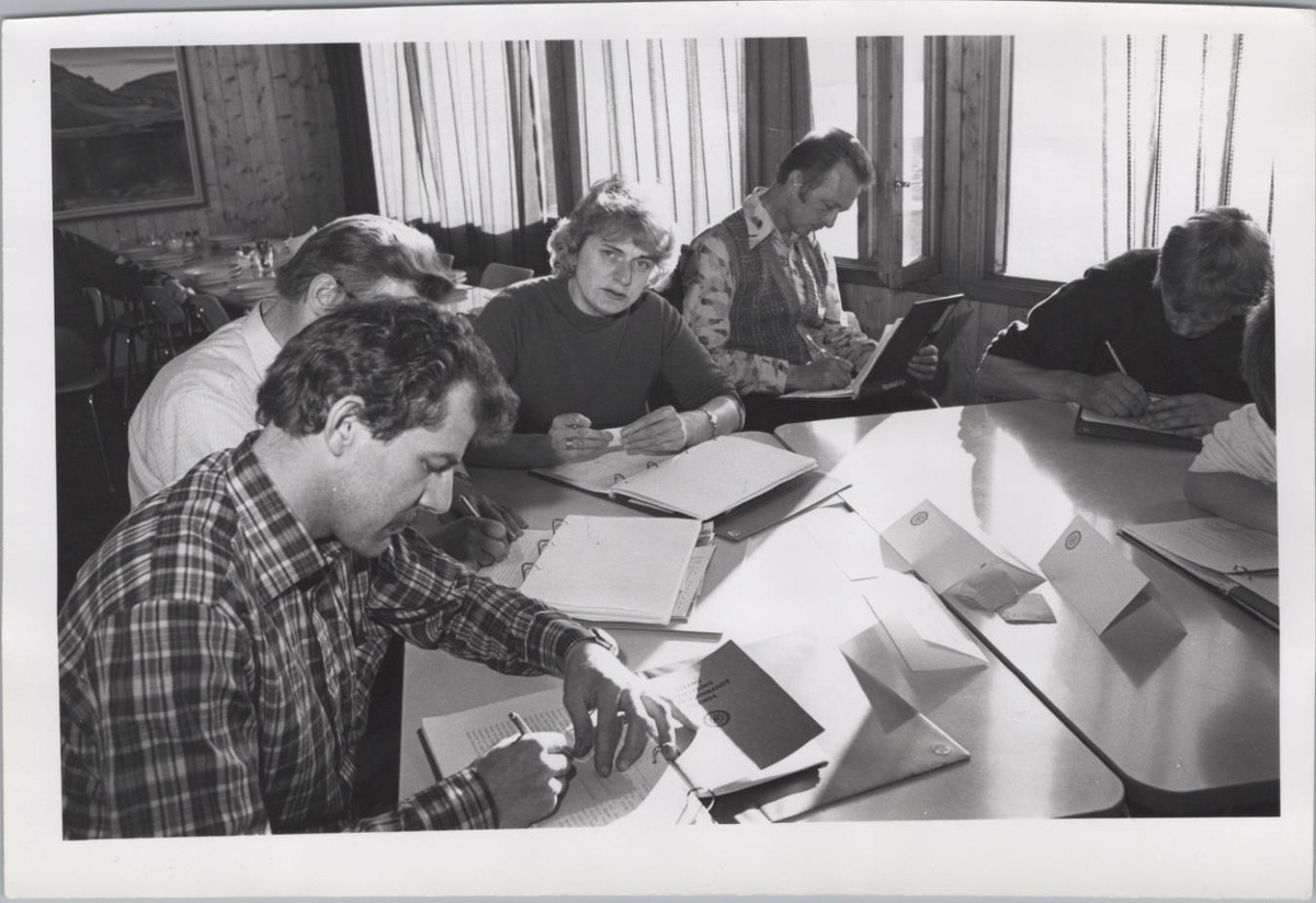 People at a meeting around tables in the dining room of Hótel Flókalundur