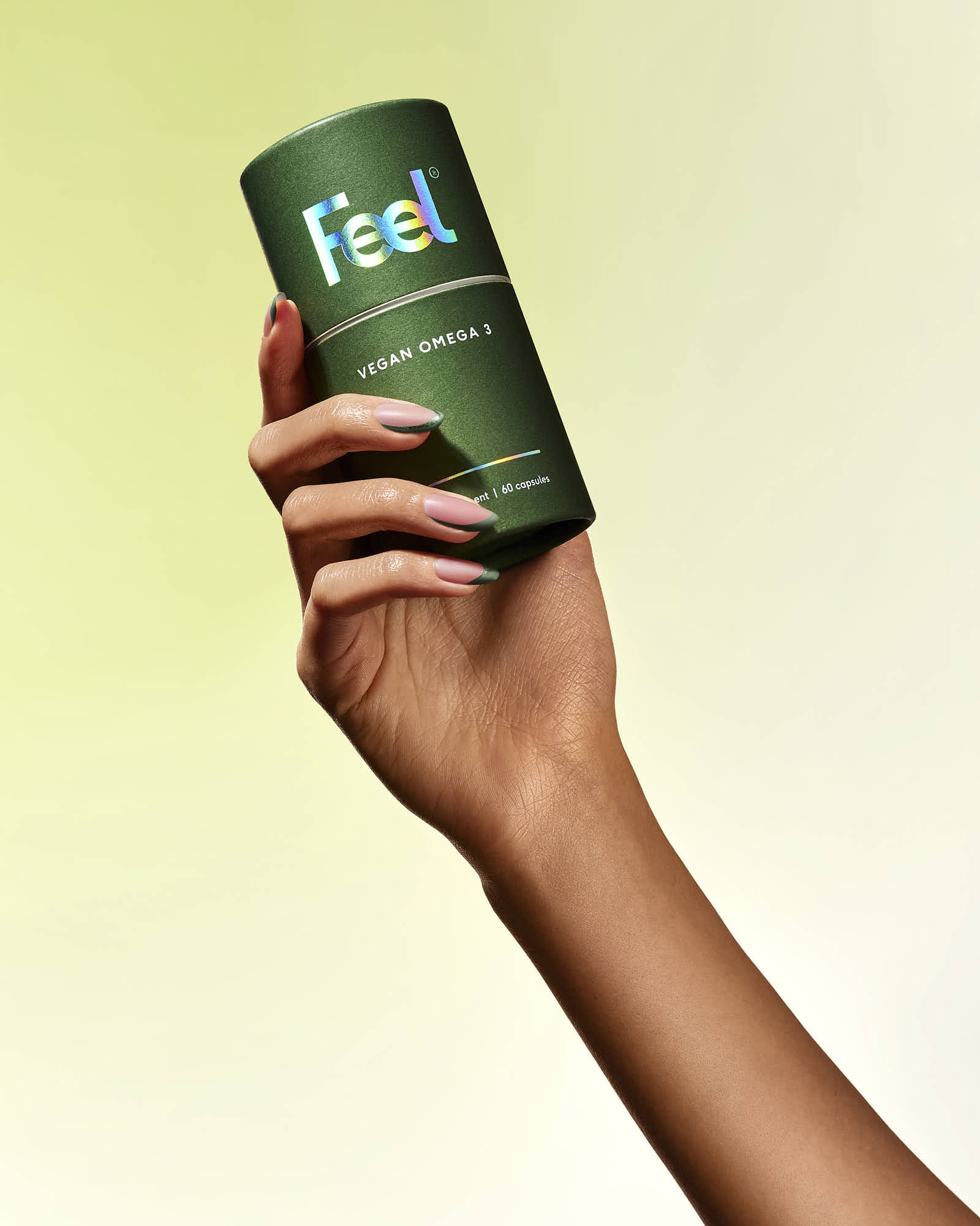 A hand holds a green can against a soft, neutral background.