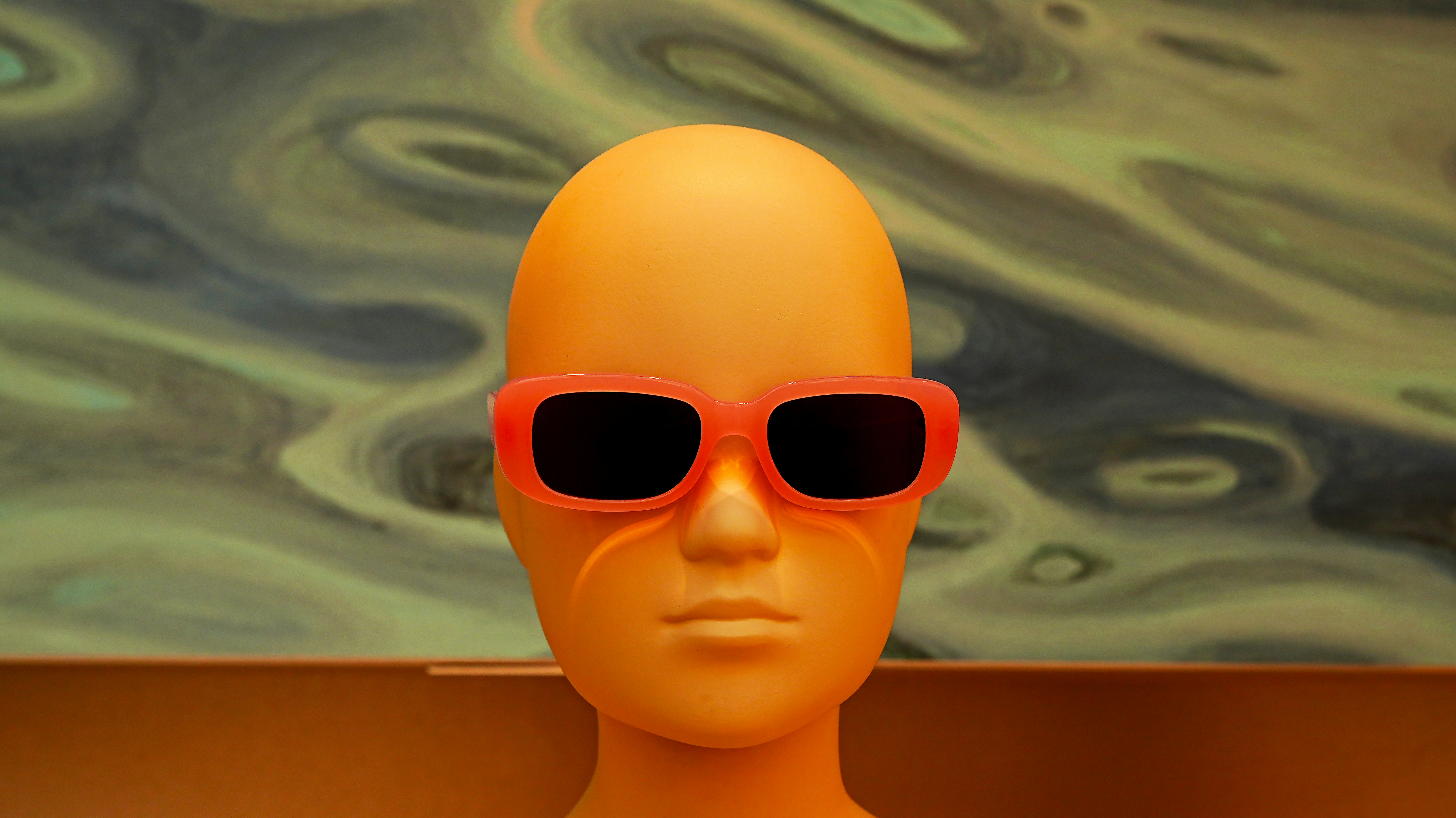 Minimal 3D head wearing red sunglasses on an abstract background