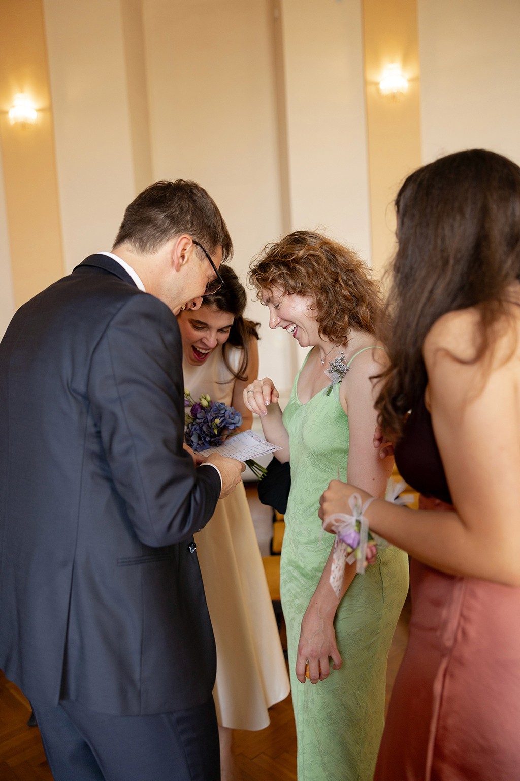 Married couple standing with their friends, looking at a wedding gift and laughing