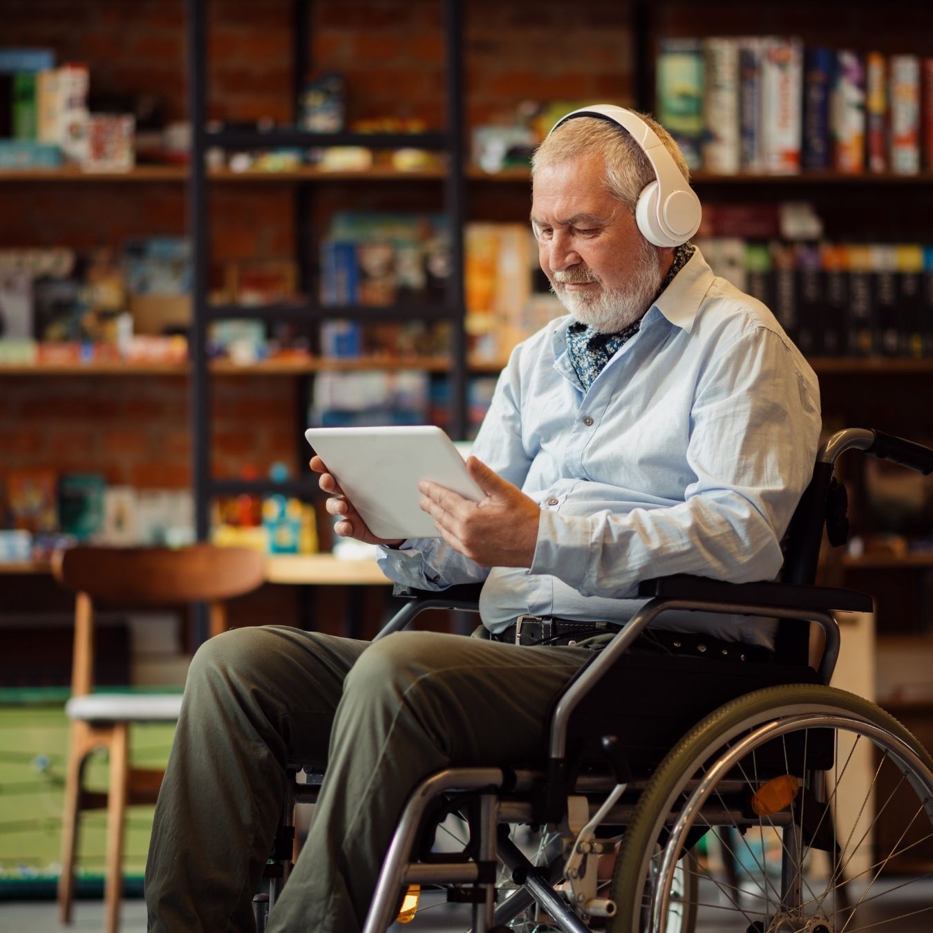 A person in a powerchair and a person sitting on a couch listening to a podcast together