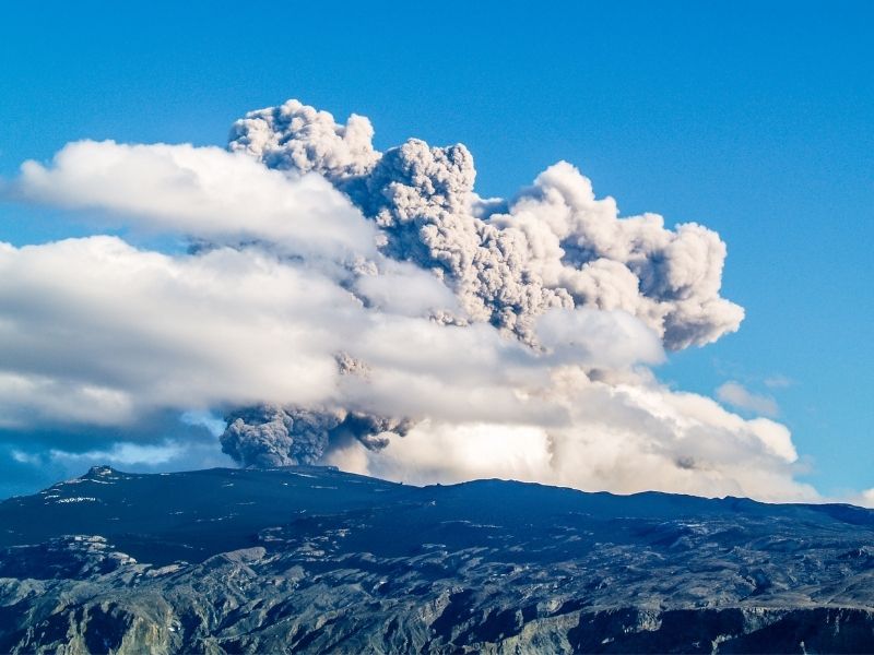 Large ash plume rising high into the sky from Eyjafjallajökull volcano in Iceland during an explosive eruption, with thick clouds of ash spreading above the landscape.