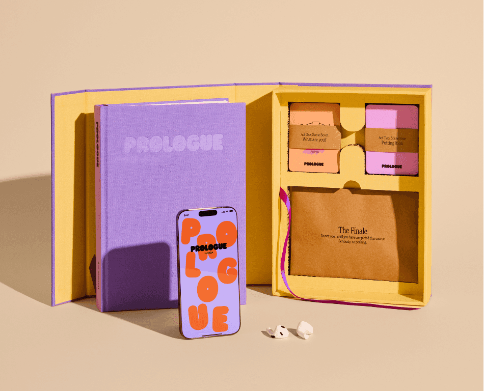 A Prologue Company Kit showcasing a journal with debossed logo, pink and orange card set, with a Brown letter in a Purple and Yellow Cover Jacket