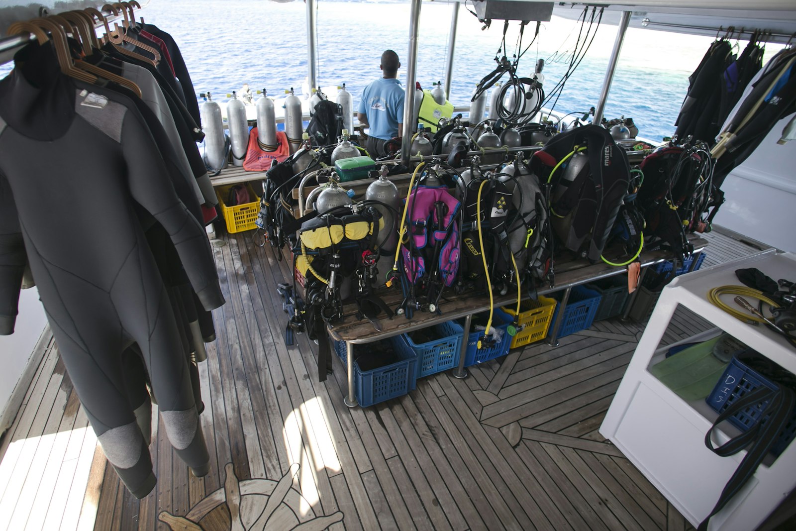 Rows of BCDs, regulators and tanks racked and ready on a dive boat