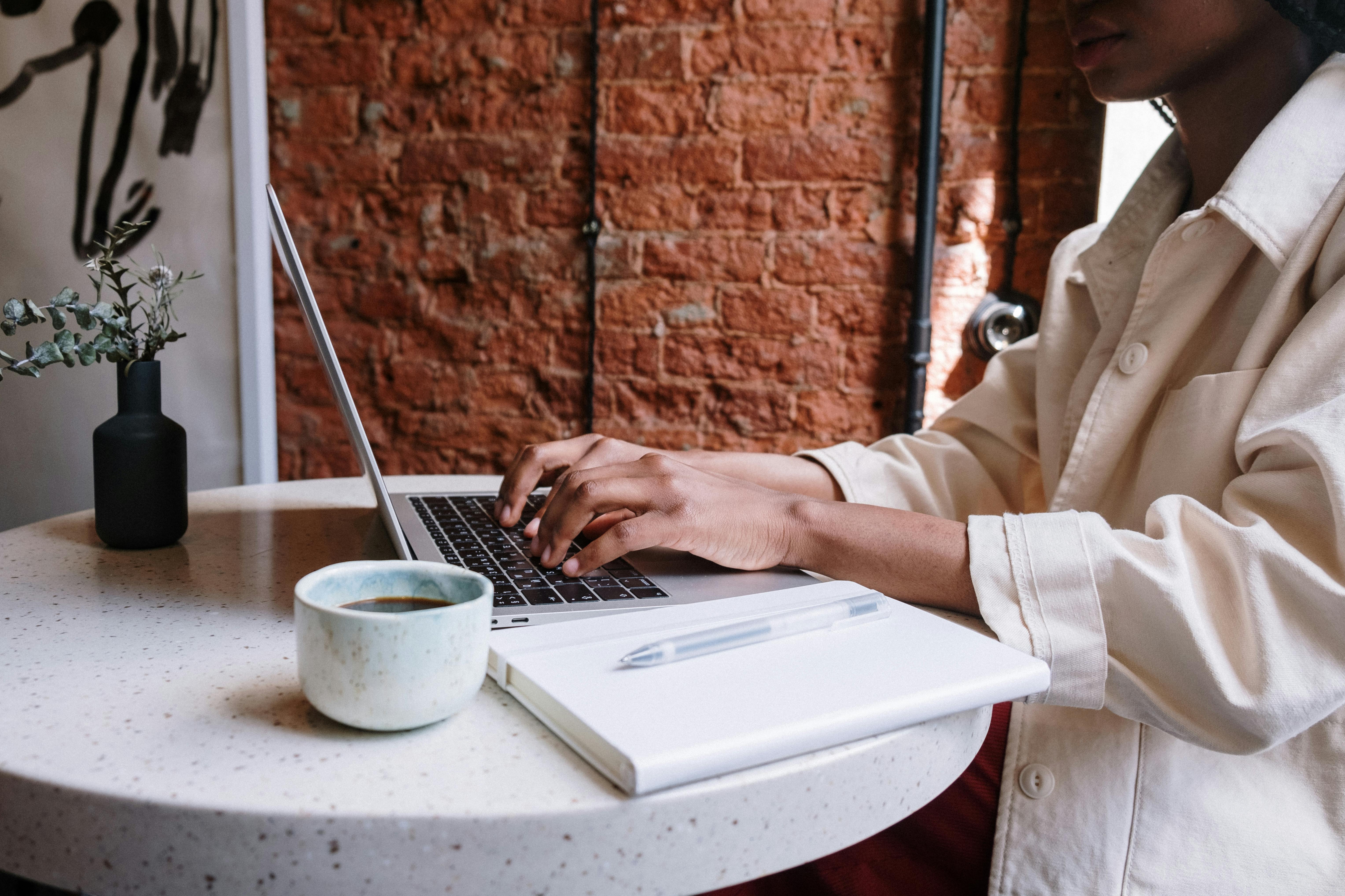 A woman typing on her laptop at a table, demonstrating concentration and engagement with her work.