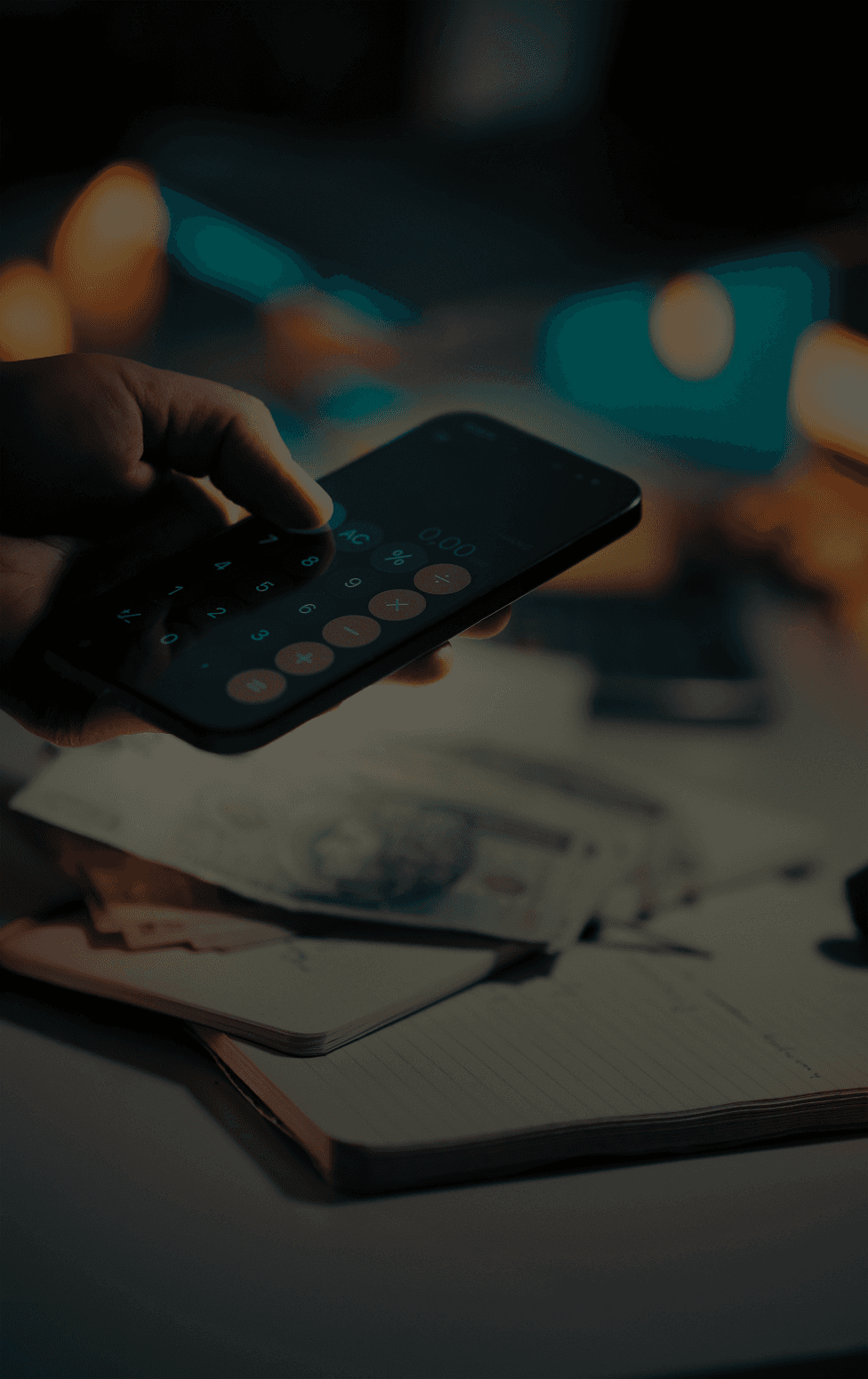 Hand using calculator on smartphone over money.