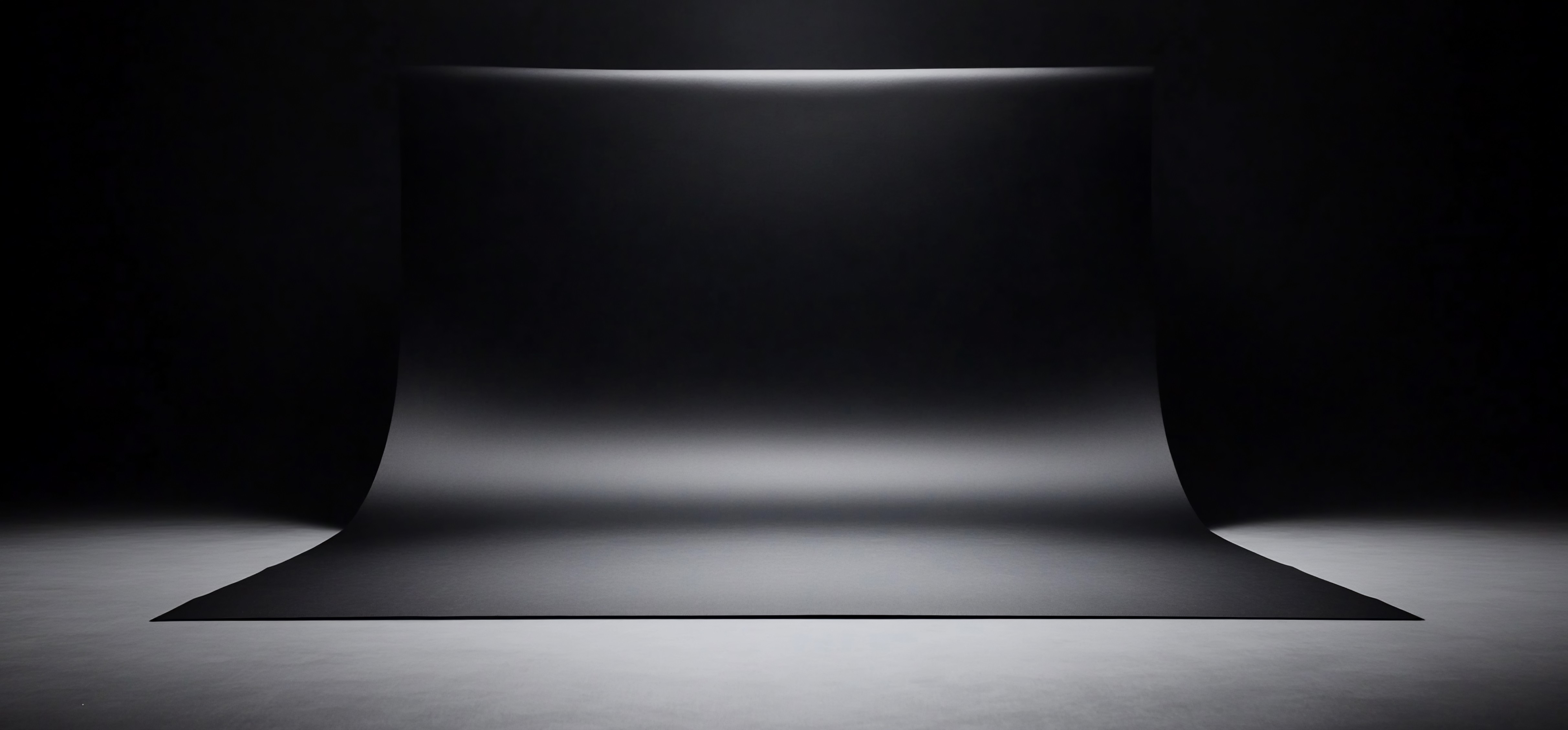 Black and white shot of a glowing laptop screen in a dark room.