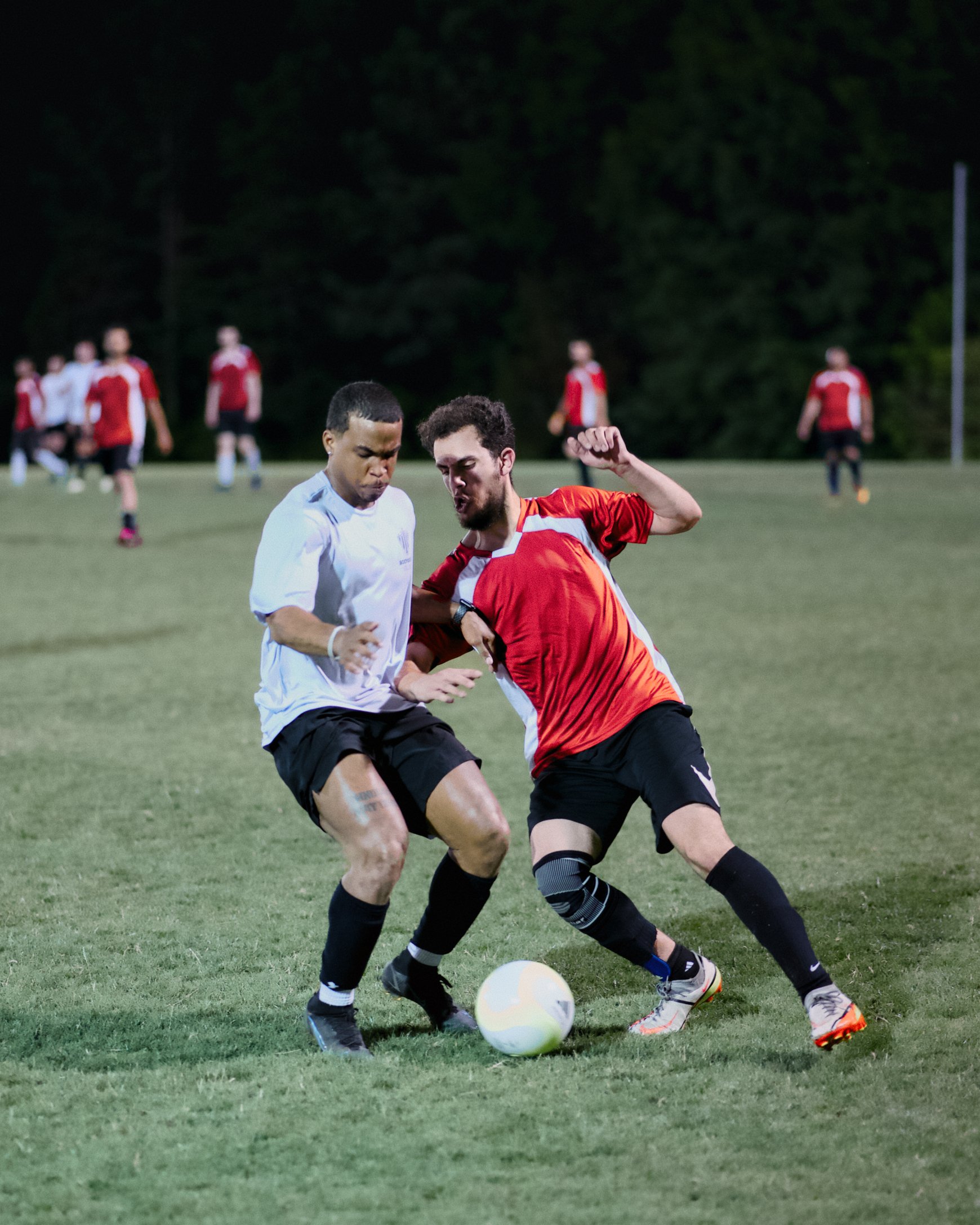 AlFursan FC player in red battles an opponent in white for the ball in Memphis