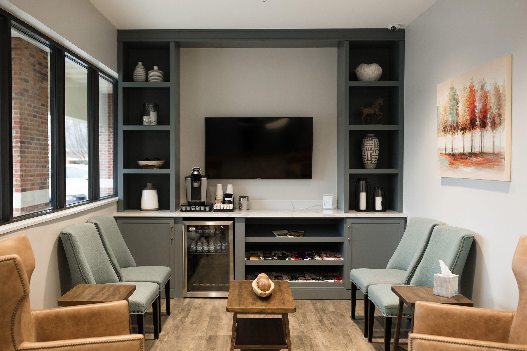 A cozy living room featuring two chairs, a coffee table, and a wall-mounted TV with shelves on both sides.