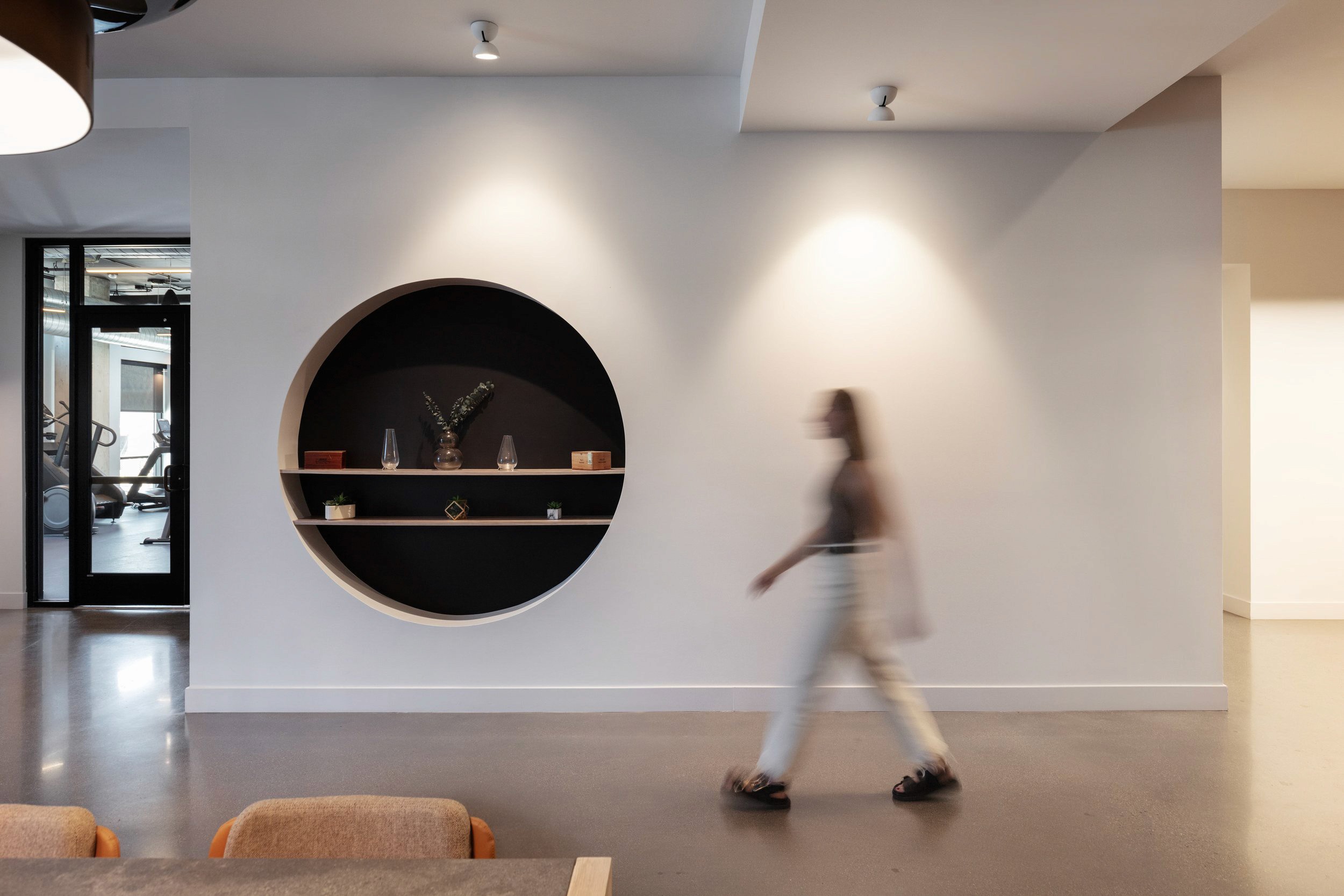 Woman walking past circular shelving with decor