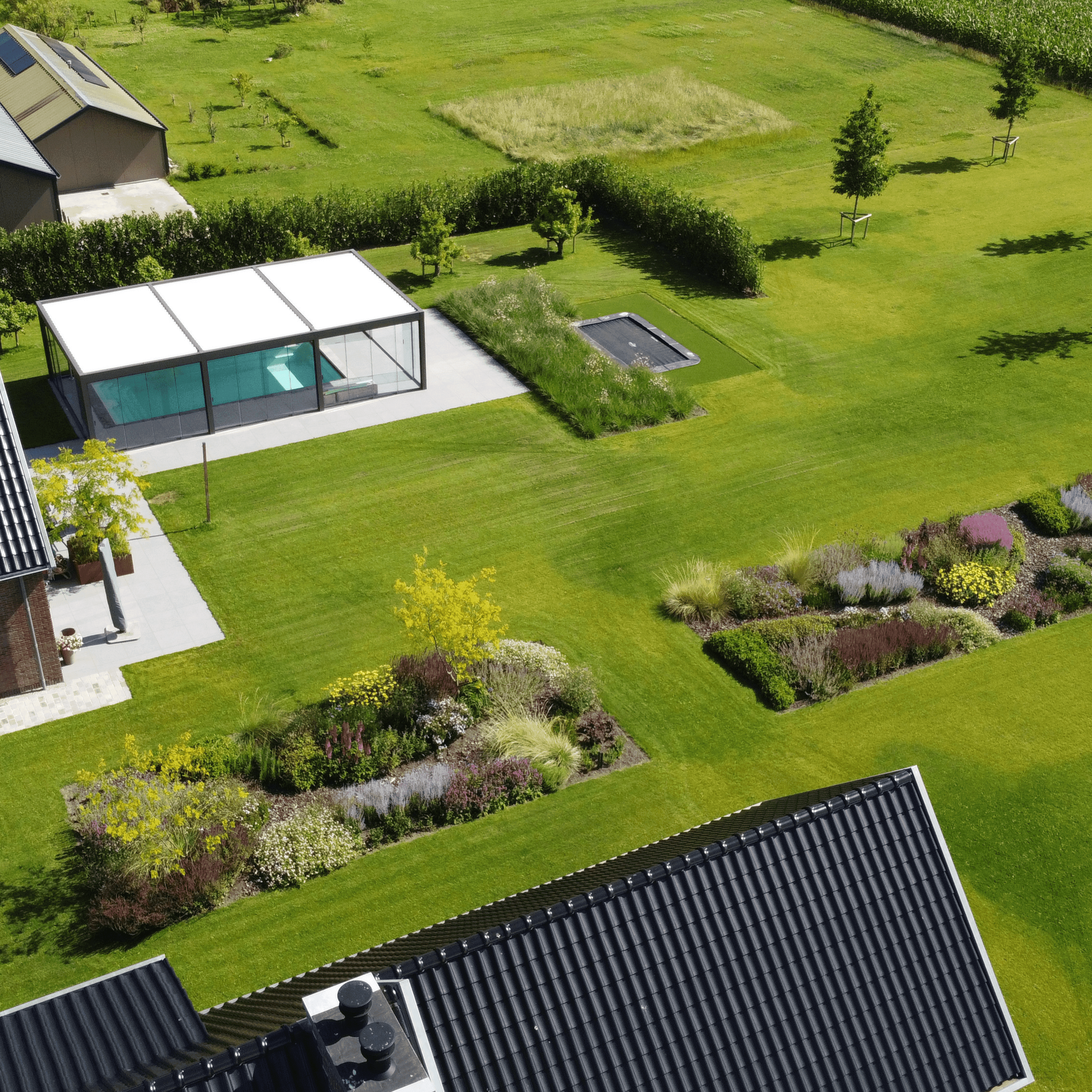 A modern, minimalist cliffside house with large glass windows offers stunning ocean views, surrounded by lush greenery and bathed in warm sunlight.