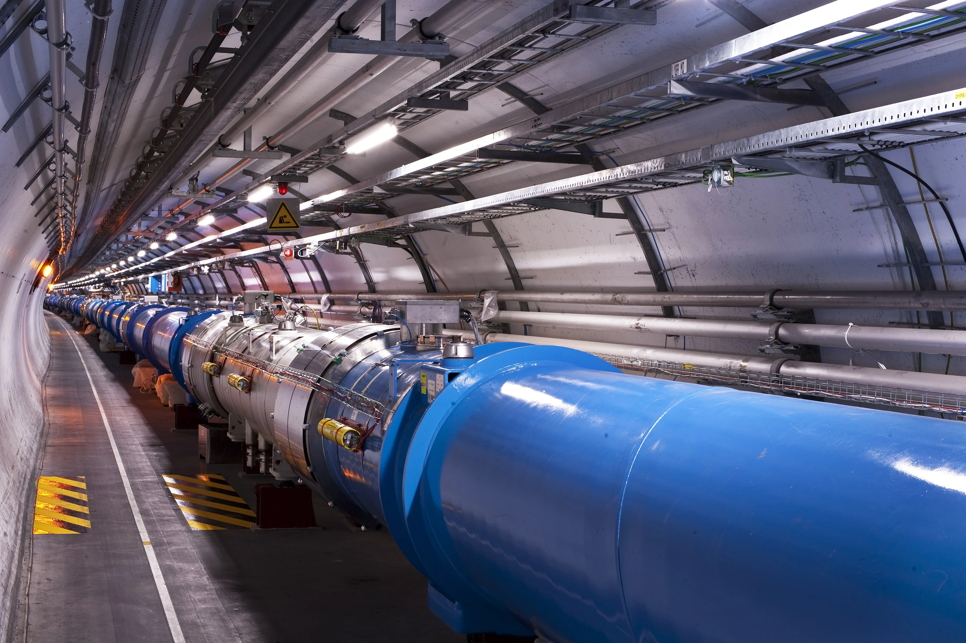 Large Hadron Collider tunnel with blue cylinders and industrial equipment
