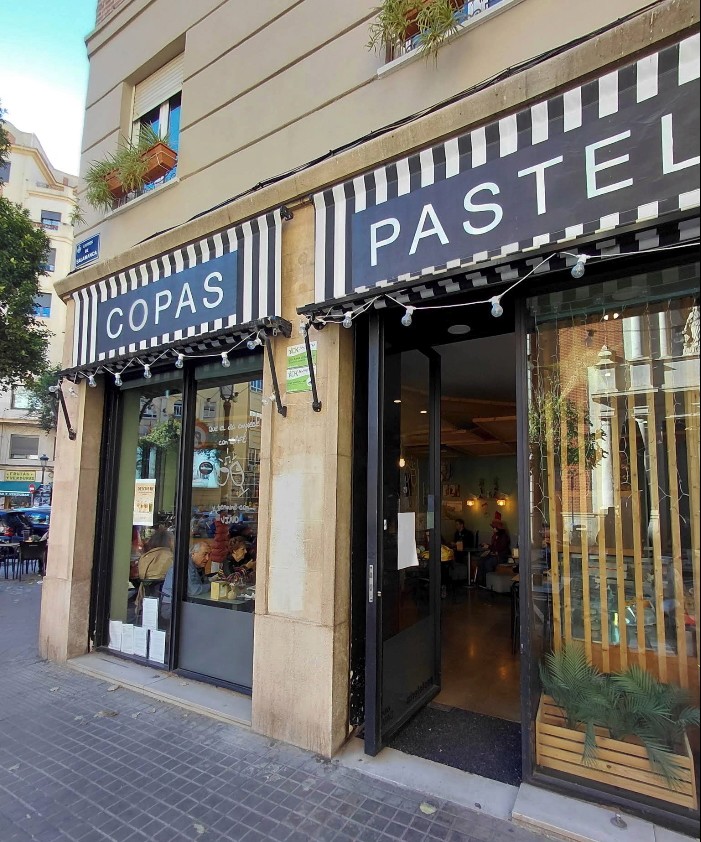 Plate with a seared salmon fillet topped with green herb garnish and sauce, served on a white dish placed on a dark green marble table beside a white candlestick.