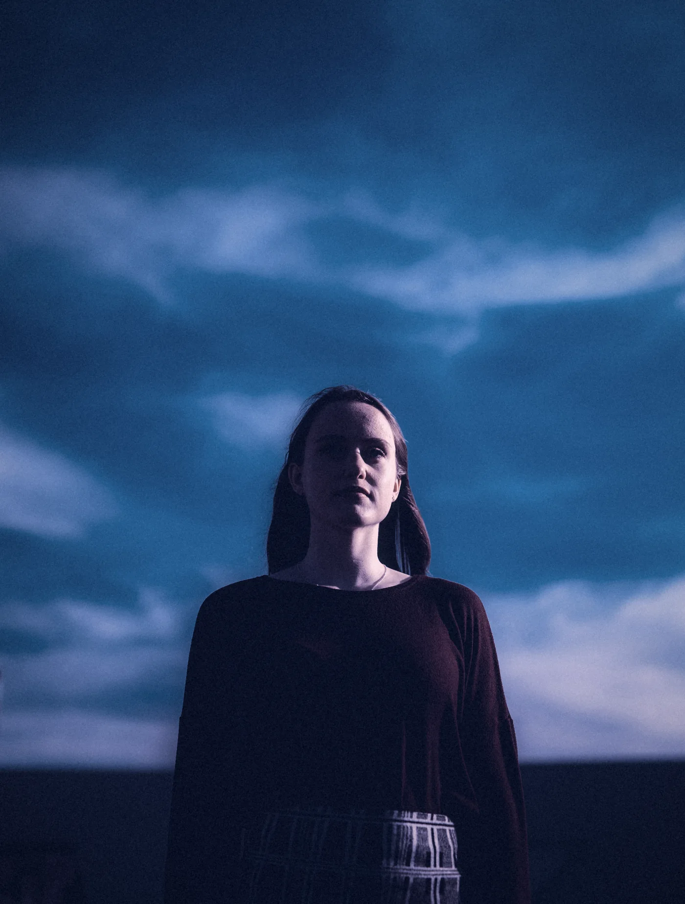 A woman under a deep blue evening sky