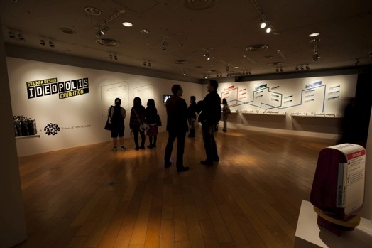 people in a dimmed light room talking and looking at the exhibition