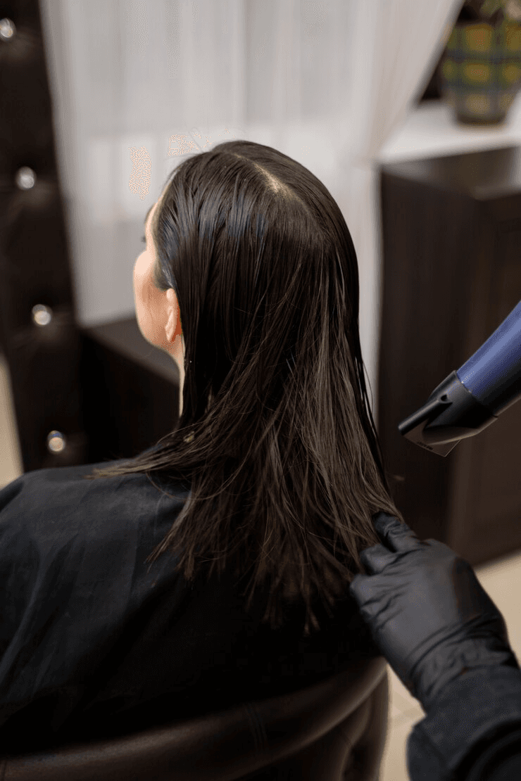 Chica con cabello oscuro de longitud media siendo secado por un estilista, durante el servicio de coloración completa en Peluquería Carlos y Hugo Spa en Arequipa