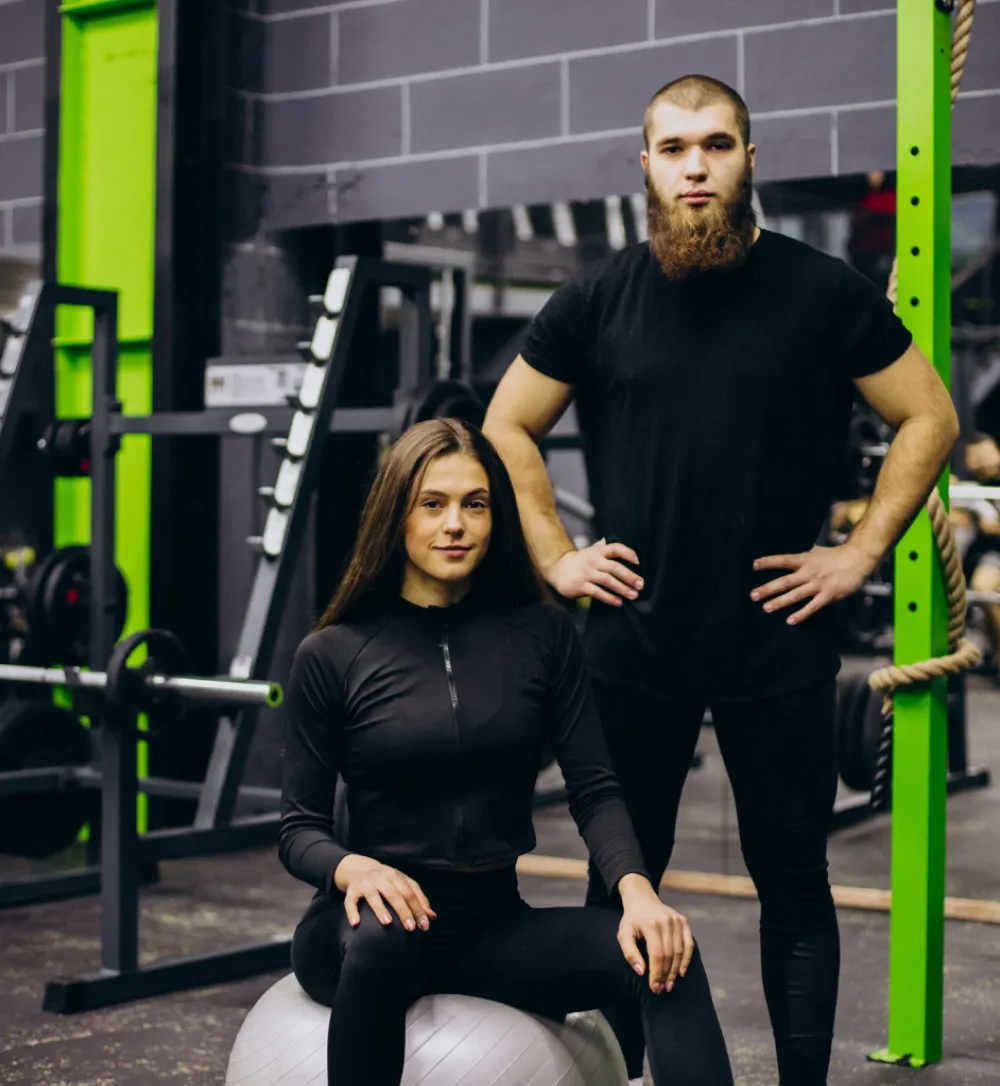 A man and woman pose together for a photo in a gym, showcasing a friendly and active atmosphere.