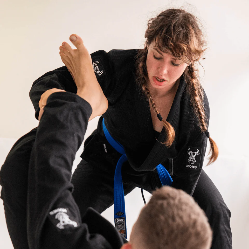 female jiu jitsu practitioner grappling wearing Hooks gi