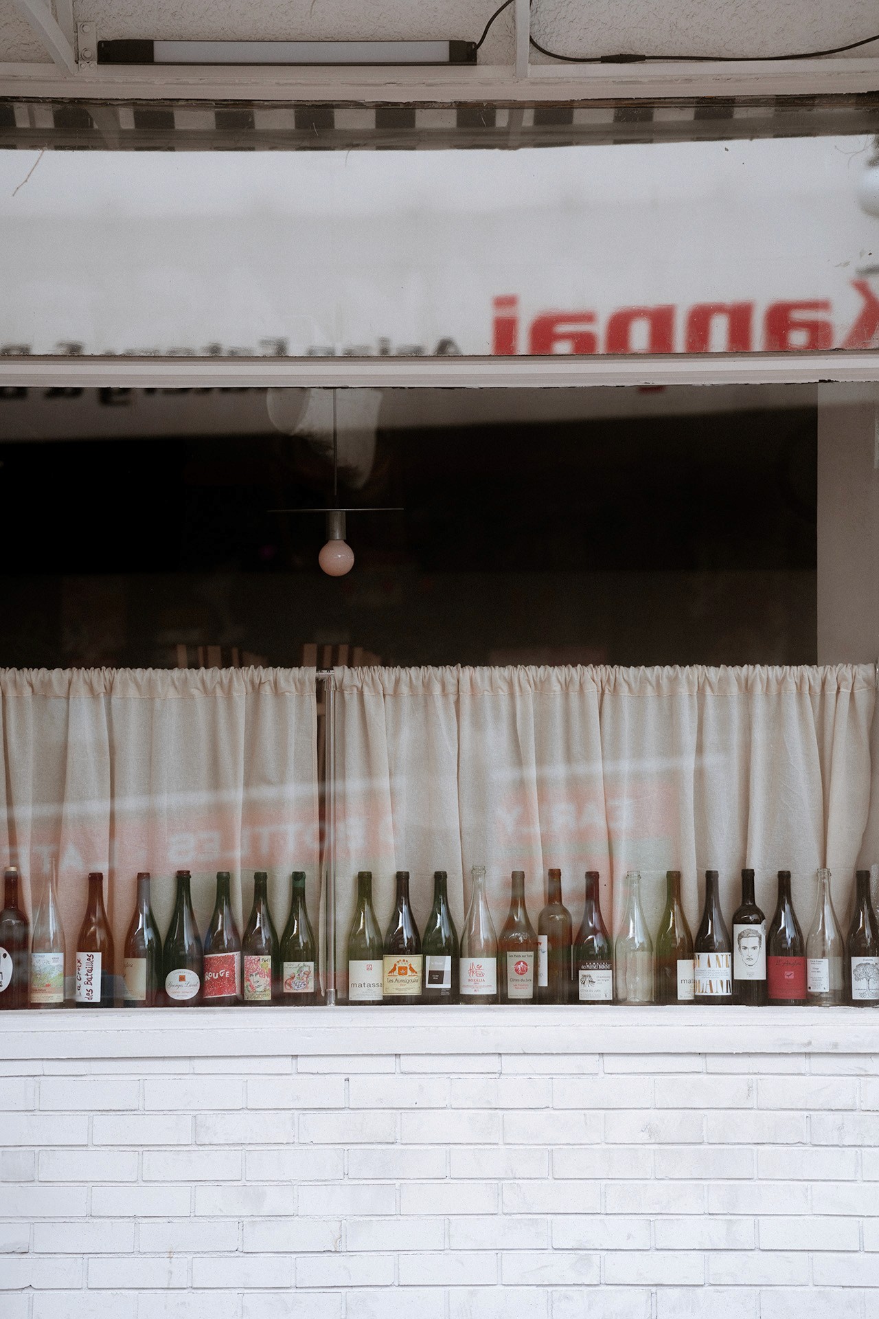 a storefront window with empty wine bottles lining the windowsill