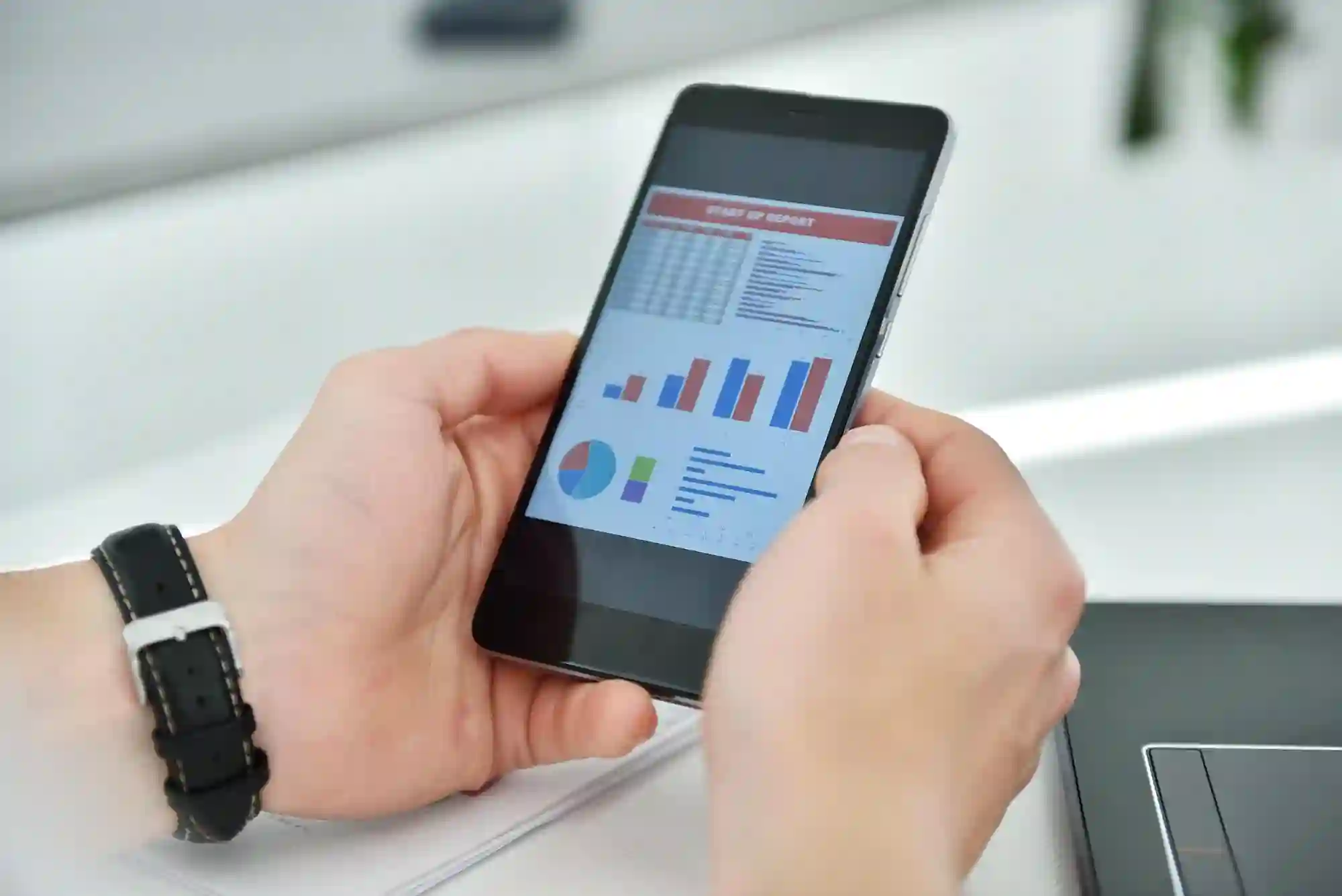 A close-up of a creator's hands holding a phone, diagnosing video performance reports and charts.