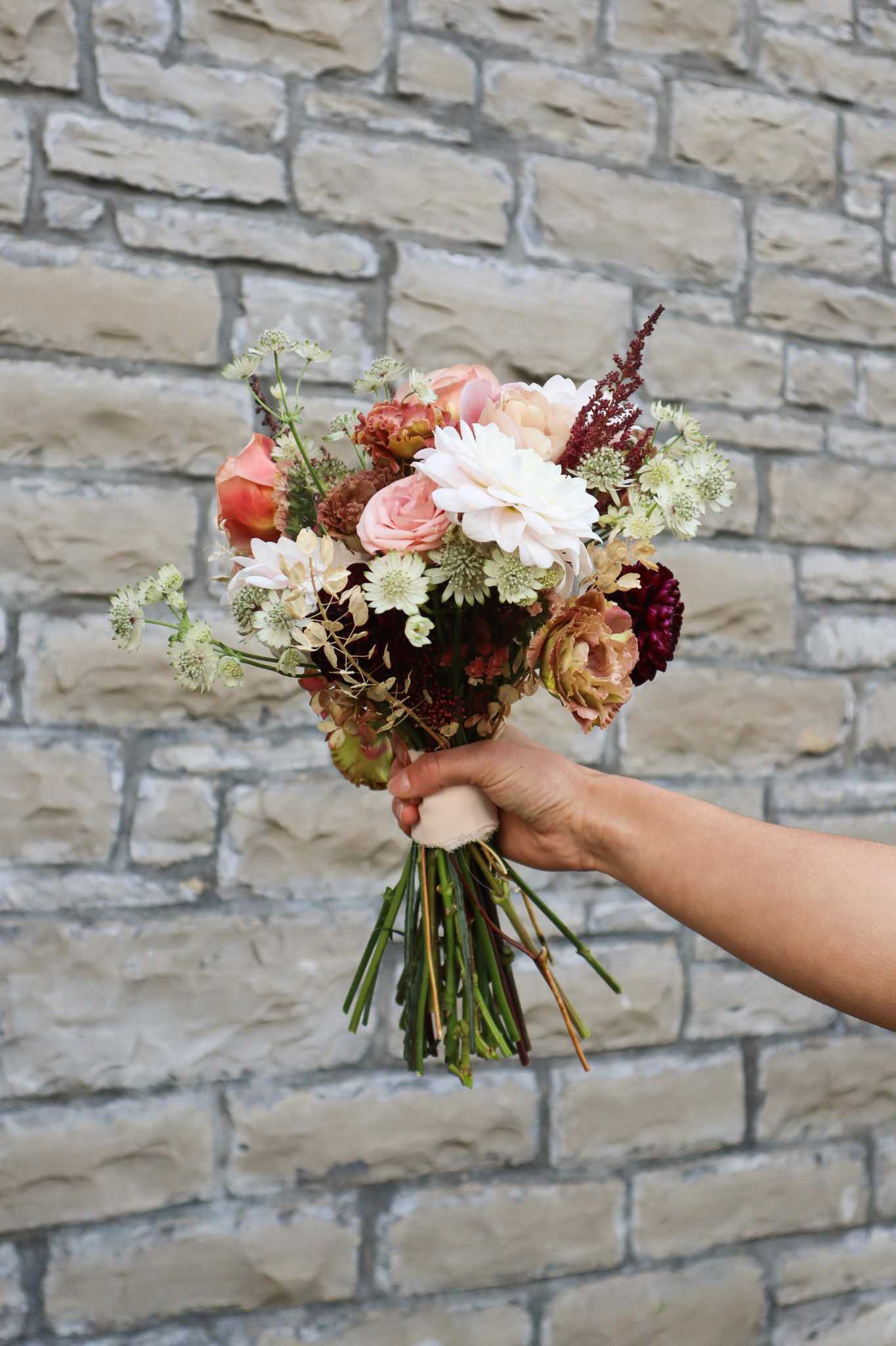 Autumn flower bouquet held in fron of Ashlar stone walls