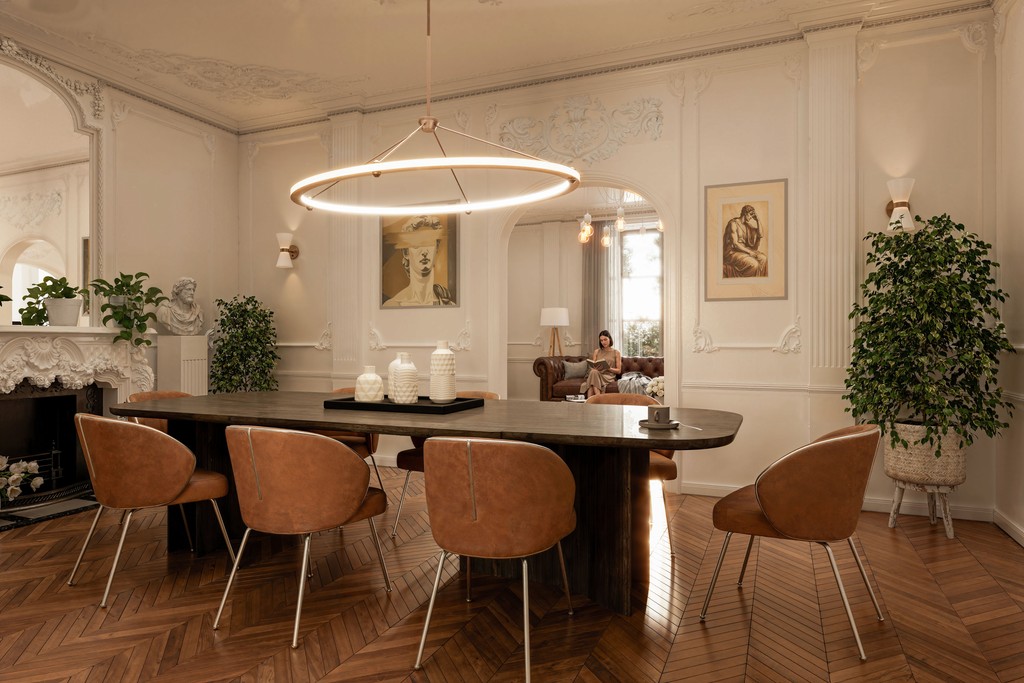Luxury Parisian dining room interior design featuring ornate white plaster stucco mouldings, dark oval dining table, tan leather dining chairs, oversized circular rose gold pendant light, and herringbone parquet hardwood flooring