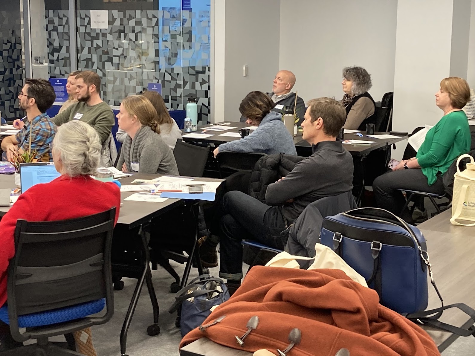 Modern home office setup with a monitor, ergonomic chair, keyboard, and indoor plants near a window with blinds.