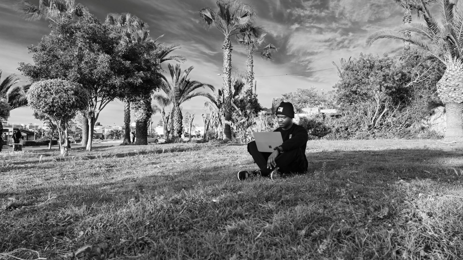 Samuel G. sumo sitting in a field with his laptop enjoying nature