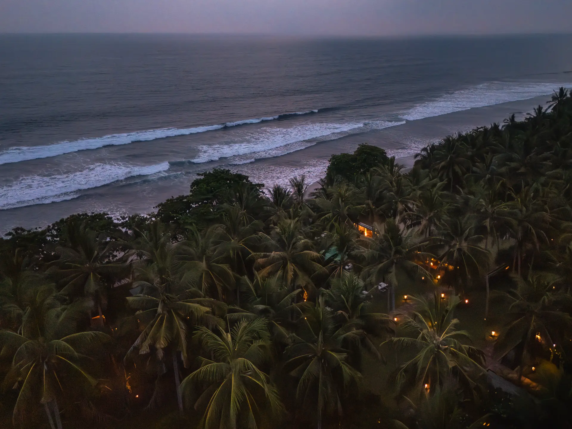 Luftaufnahme bei Dämmerung mit romantischen Lichtern – Palmenlandschaft und Ozeanblick im Kelapa Retreat & Spa Resort, Bali