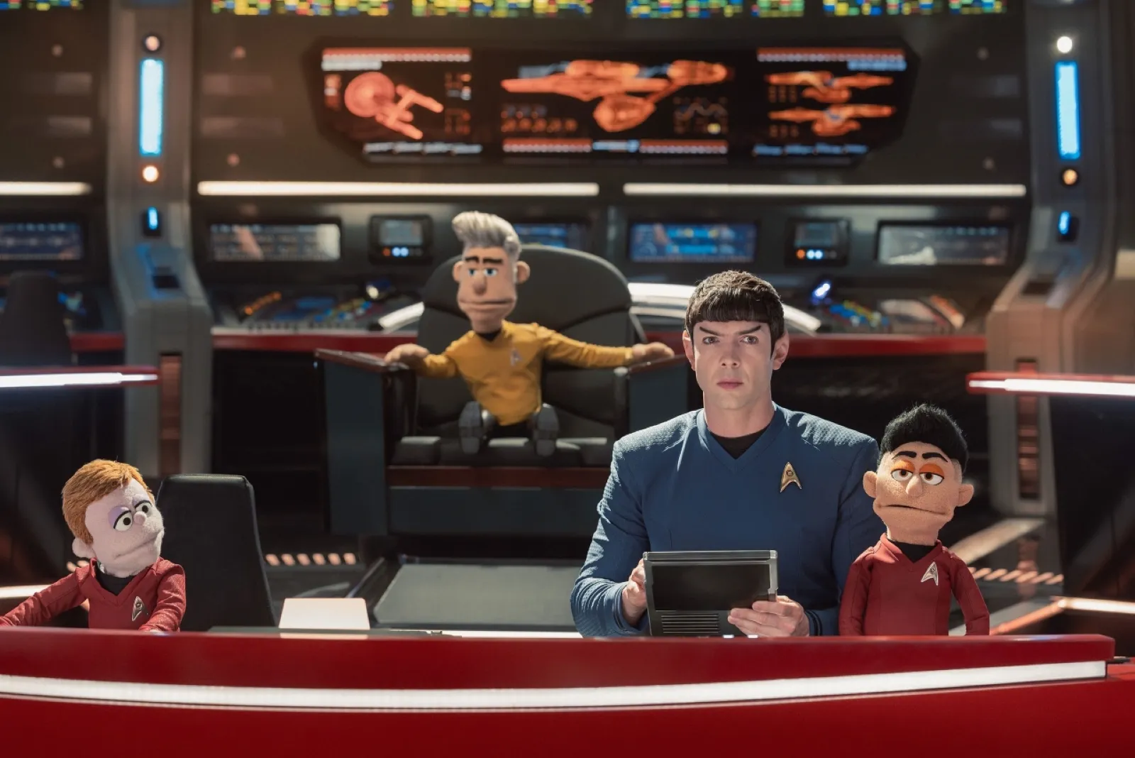 Puppet characters dressed in classic Star Trek space uniforms sit and stand on a futuristic spaceship command bridge, surrounded by high-tech screens and control panels, creating a vibrant scene reminiscent of classic sci-fi adventures.