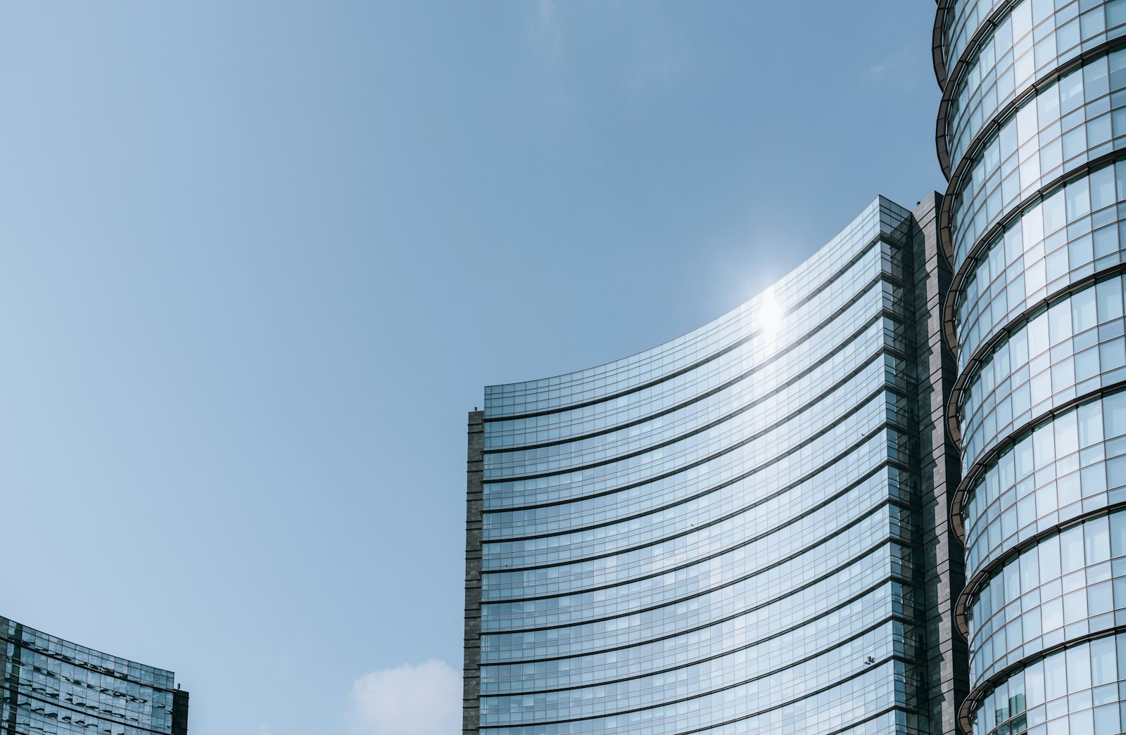 A curved glass office building against a pale sky