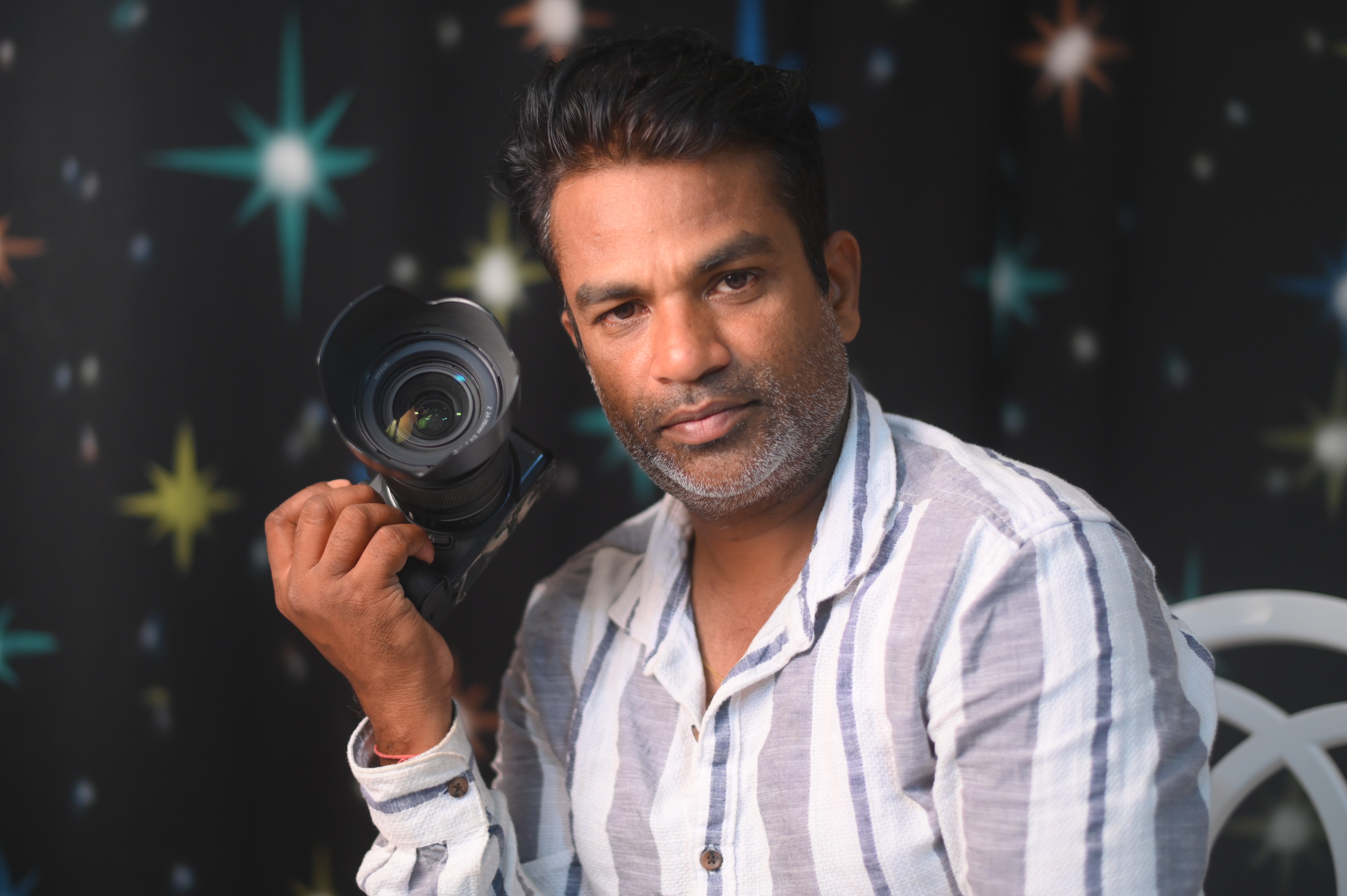 A person with short blonde hair holds a vintage camera.