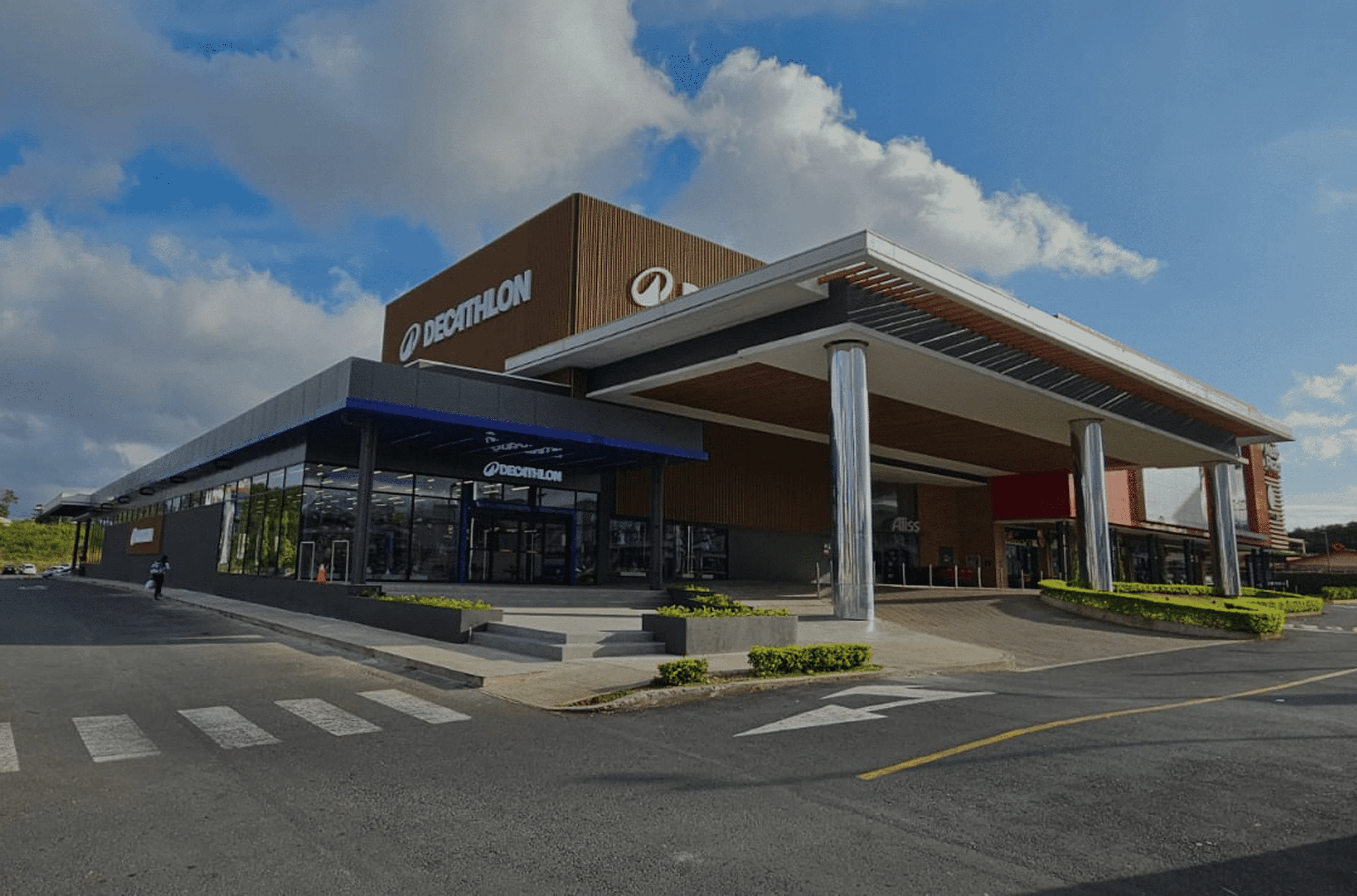 Acceso principal de la tienda Decathlon Curridabat con pórtico metálico, logotipo iluminado y amplias vitrinas.