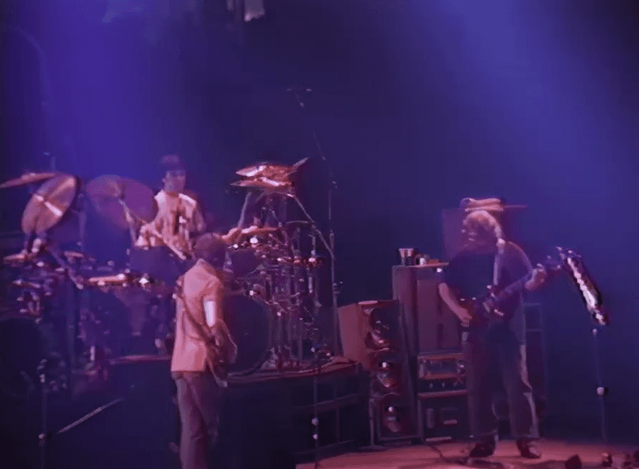 A live band performing on stage with colorful lights illuminating the scene.