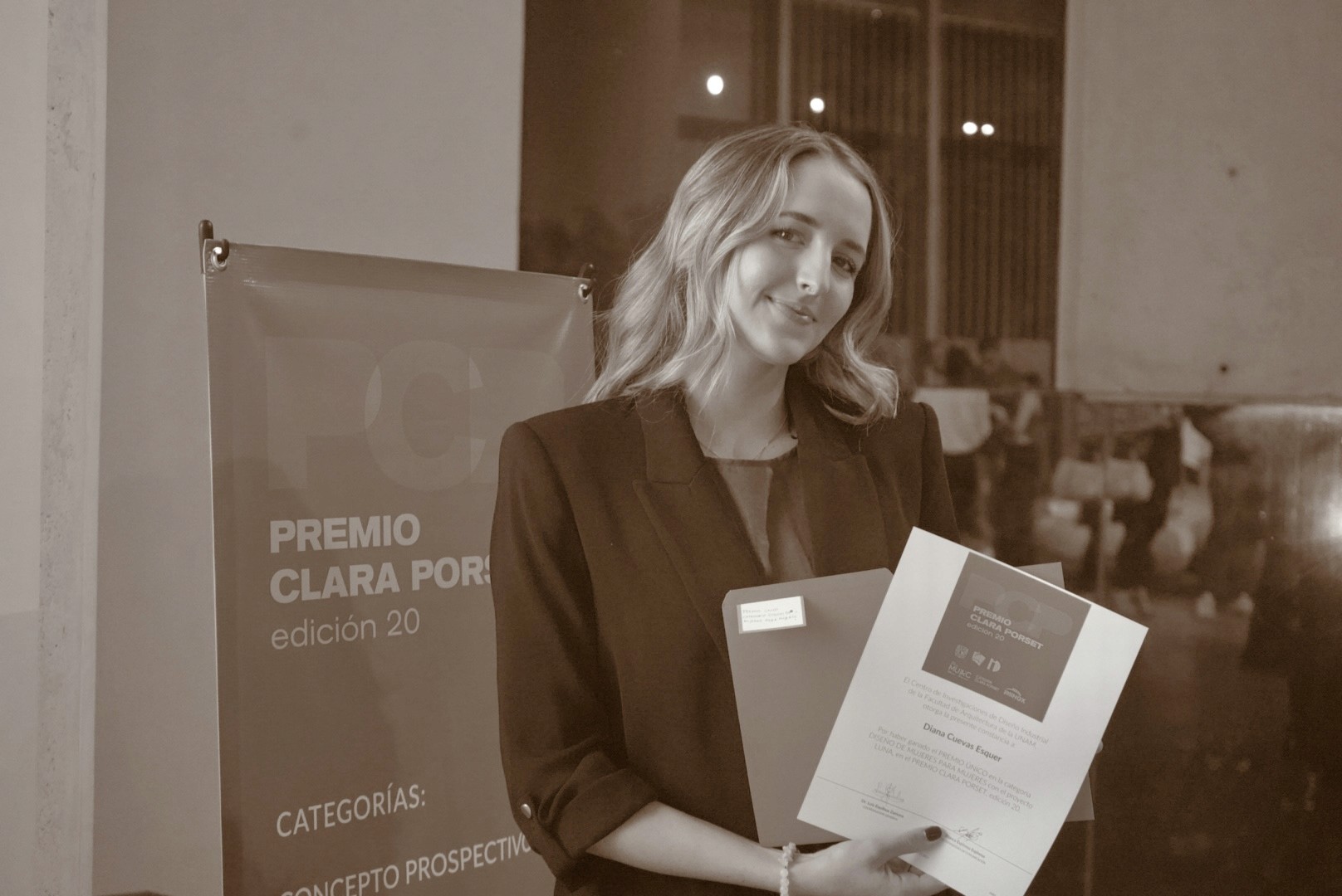 A model wearing an elegant cream blazer sits on a chair against a bright blue background, showcasing a modern and minimalist professional style.