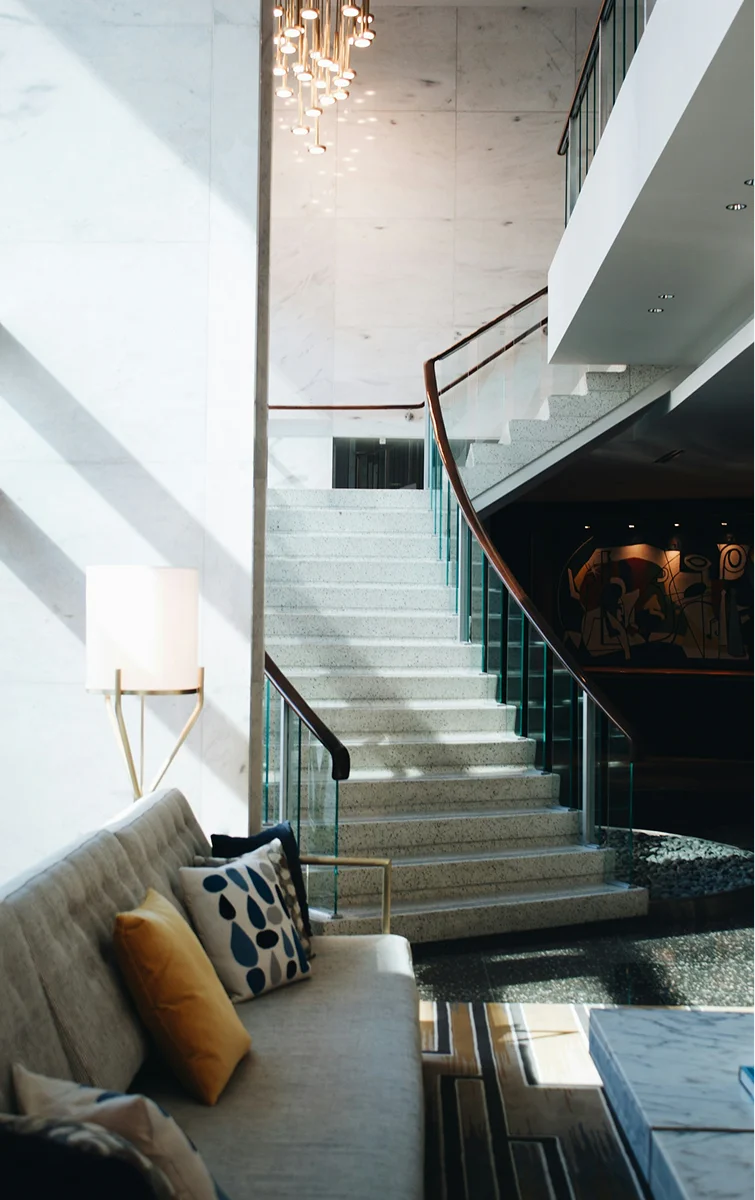 Hotel lounge with seating, marble stairs, and pendant lights.