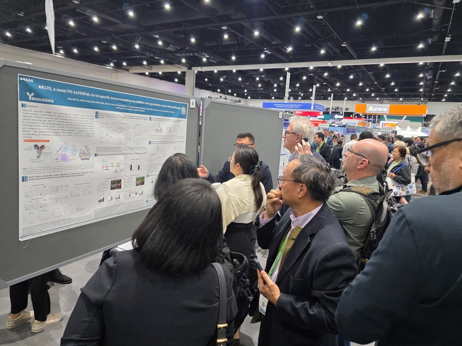 (사진1) AACR 2026_와이바이오로직스 AR170 포스터 앞에서 설명 듣고 있는 업계 관계자들