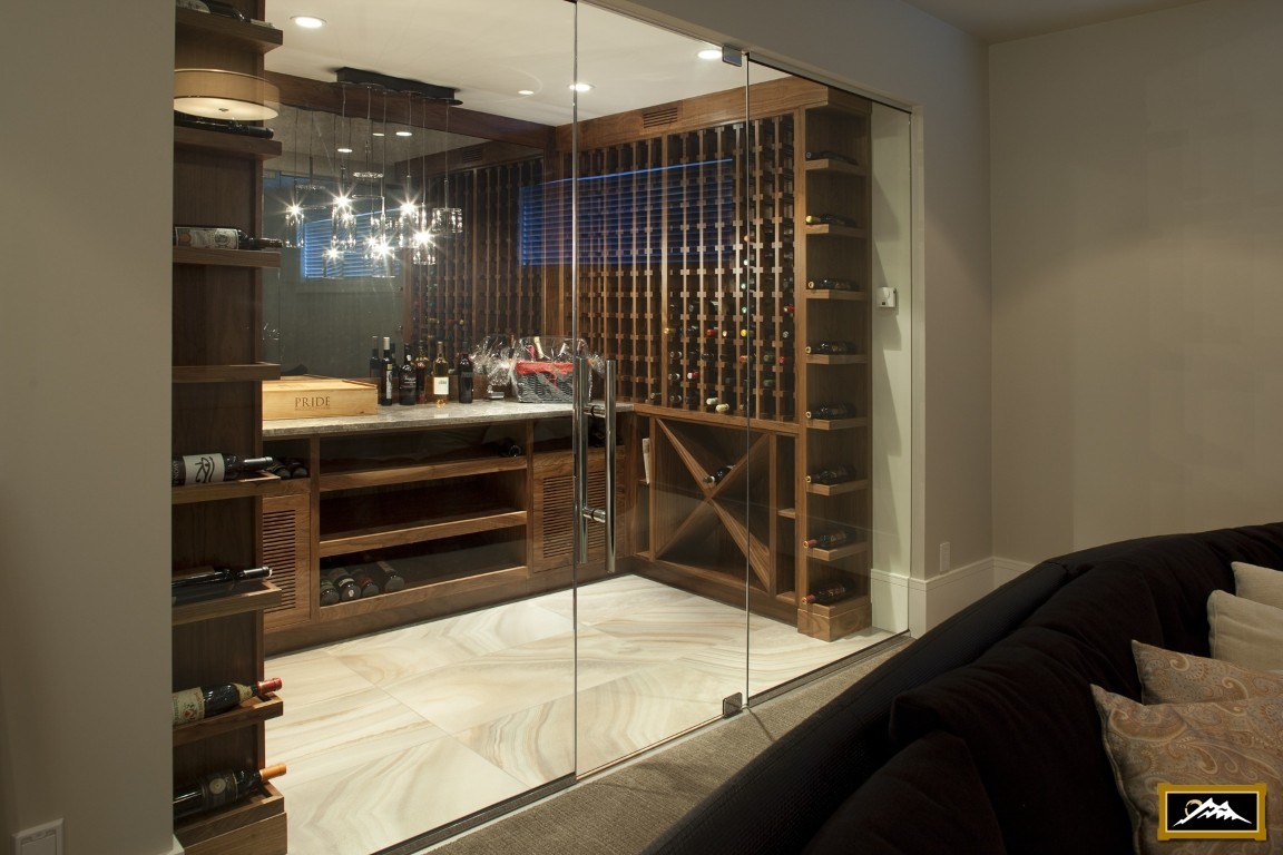 Image of Luxury wine cellar with glass door, wooden shelves, and marble countertop designed by KHD Homes.