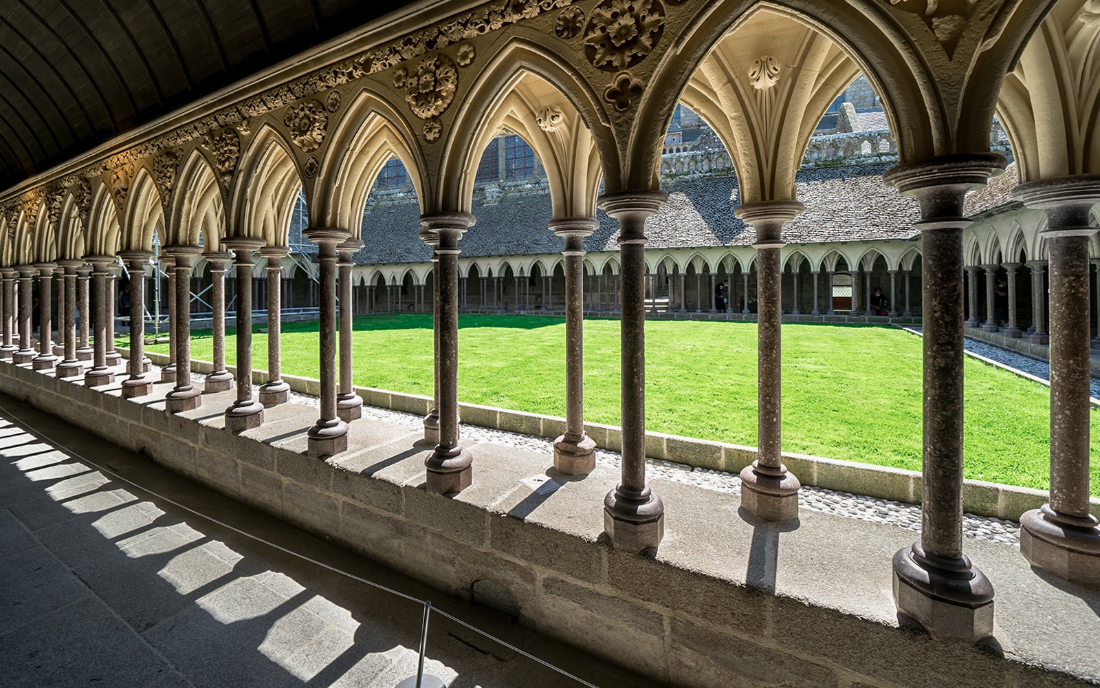 Cloister arches and green courtyard at Mont Saint Michel, France.