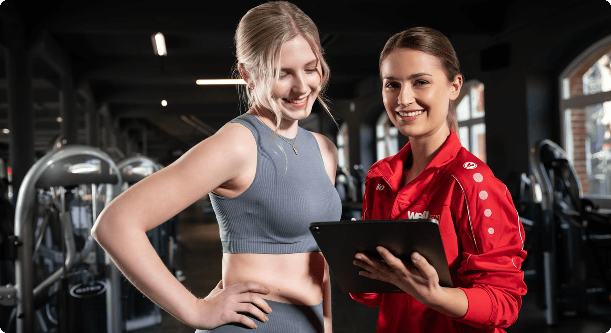 Two women are standing in front of a tablet with the words the girl is holding it