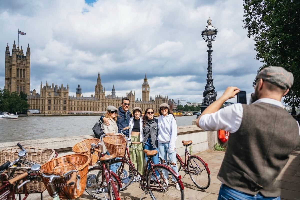 Group of friends on a guided London bike tour outside the Houses of Parliament, vintage‑style bicycles with wicker baskets on a top‑rated London cycling tour