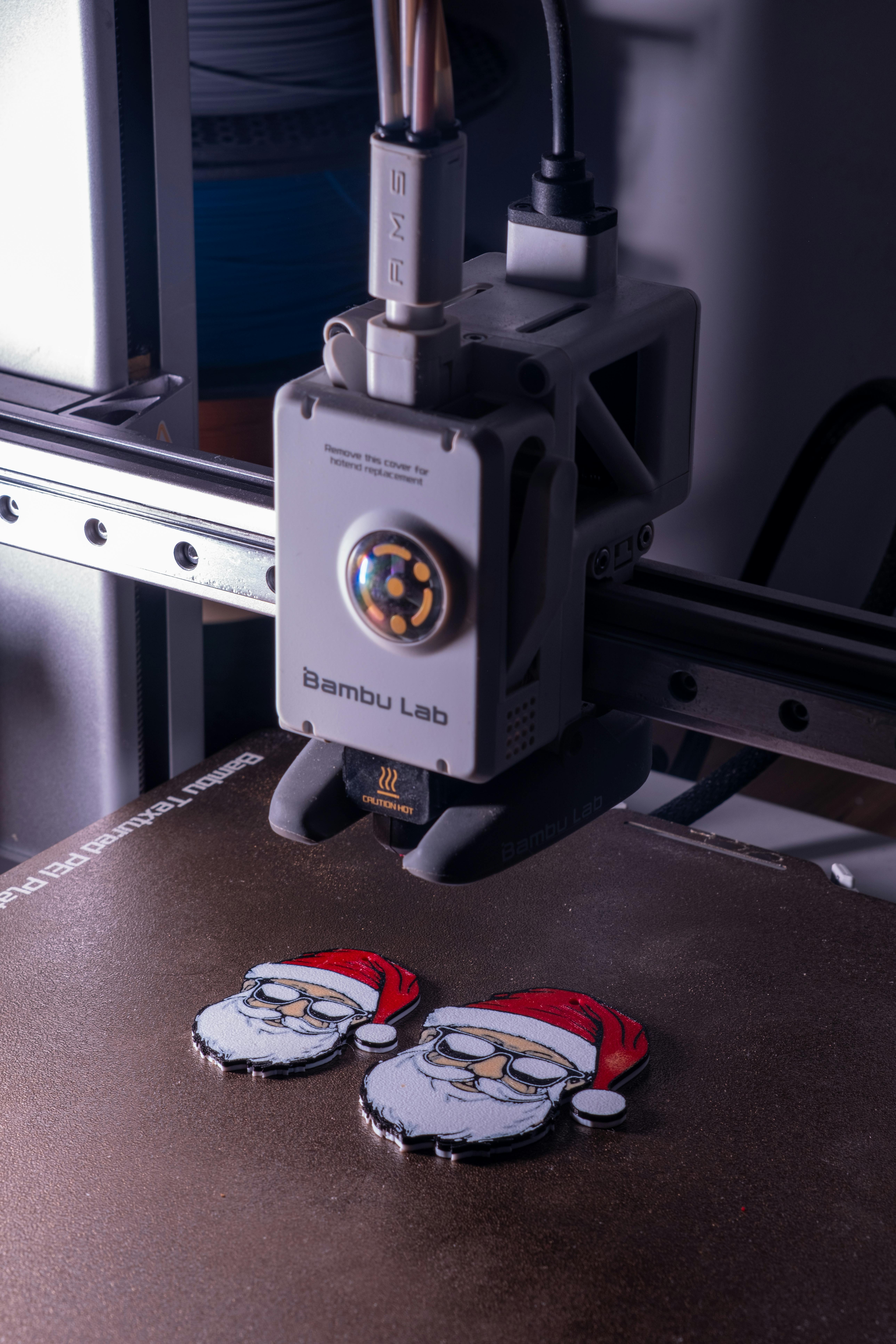 Een 3D-printer die twee kerstmanfiguren print, met gedetailleerde rode kerstmutsen. De foto toont moderne 3D-printtechniek tijdens een productieproces in december.