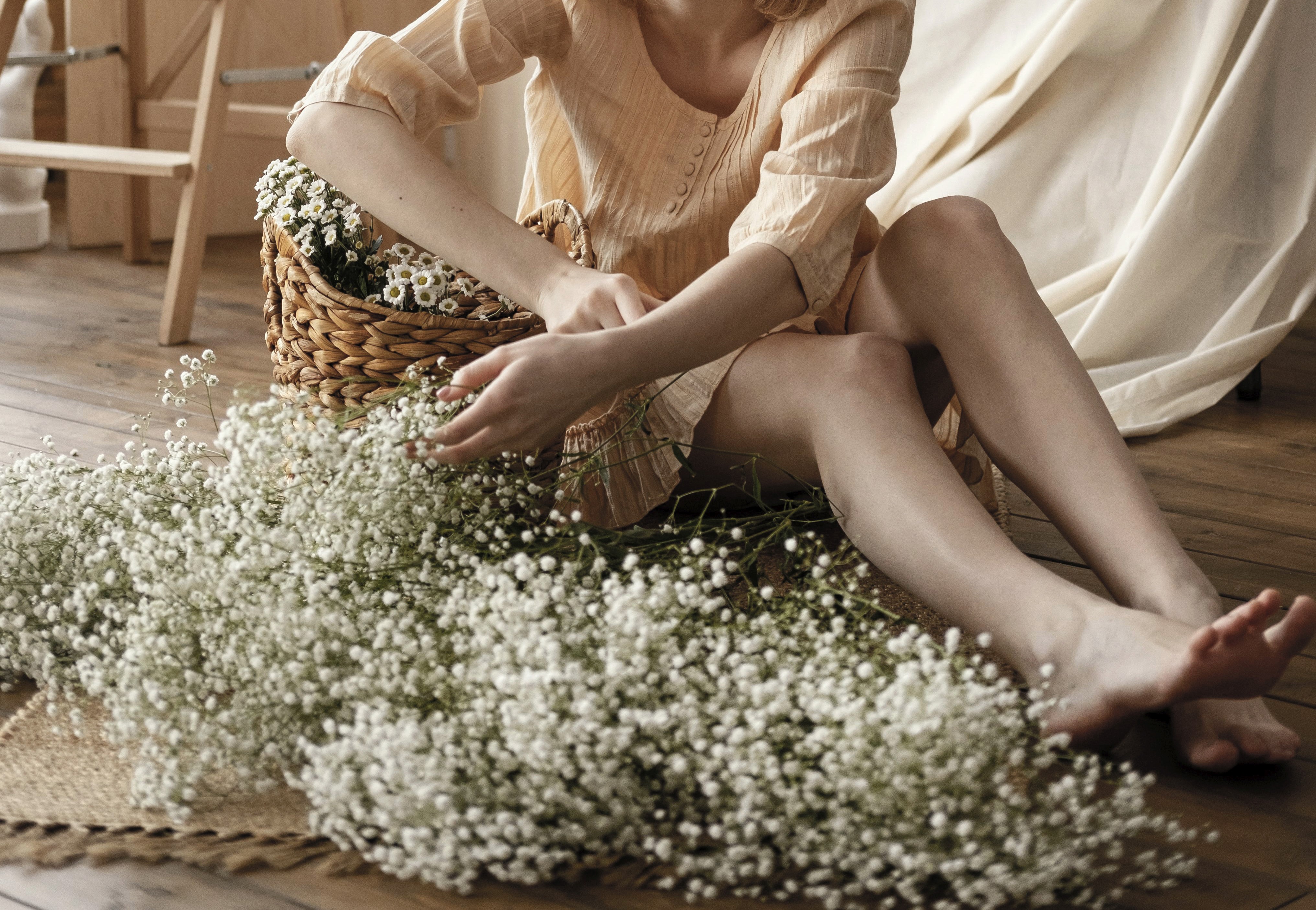 Vrouw die zich deels verschuilt achter een beige gordijn, symbool voor kwetsbaarheid en stilte rondom hormonale klachten